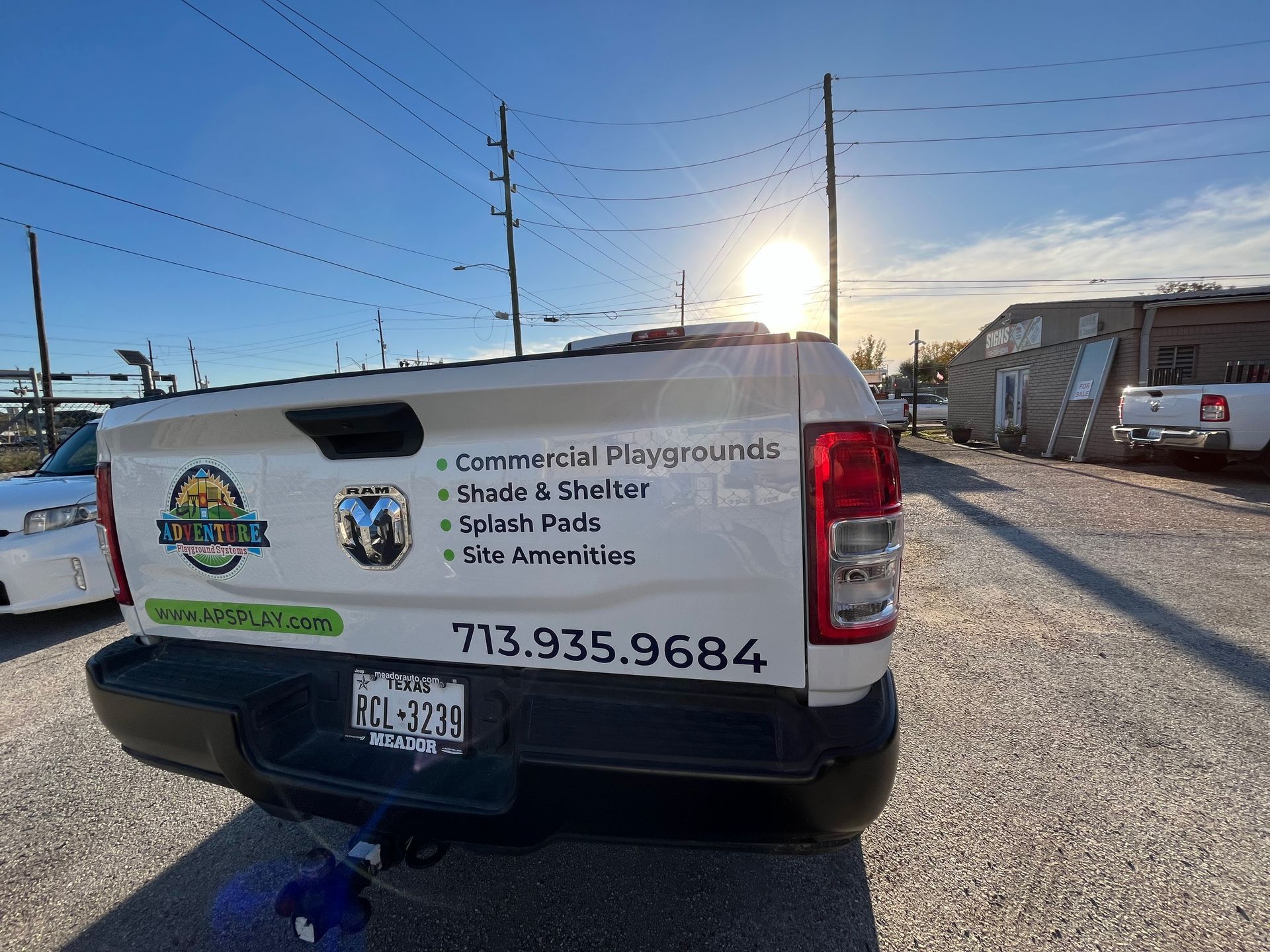 White pickup truck with business logo parked outdoors. Text reads 
