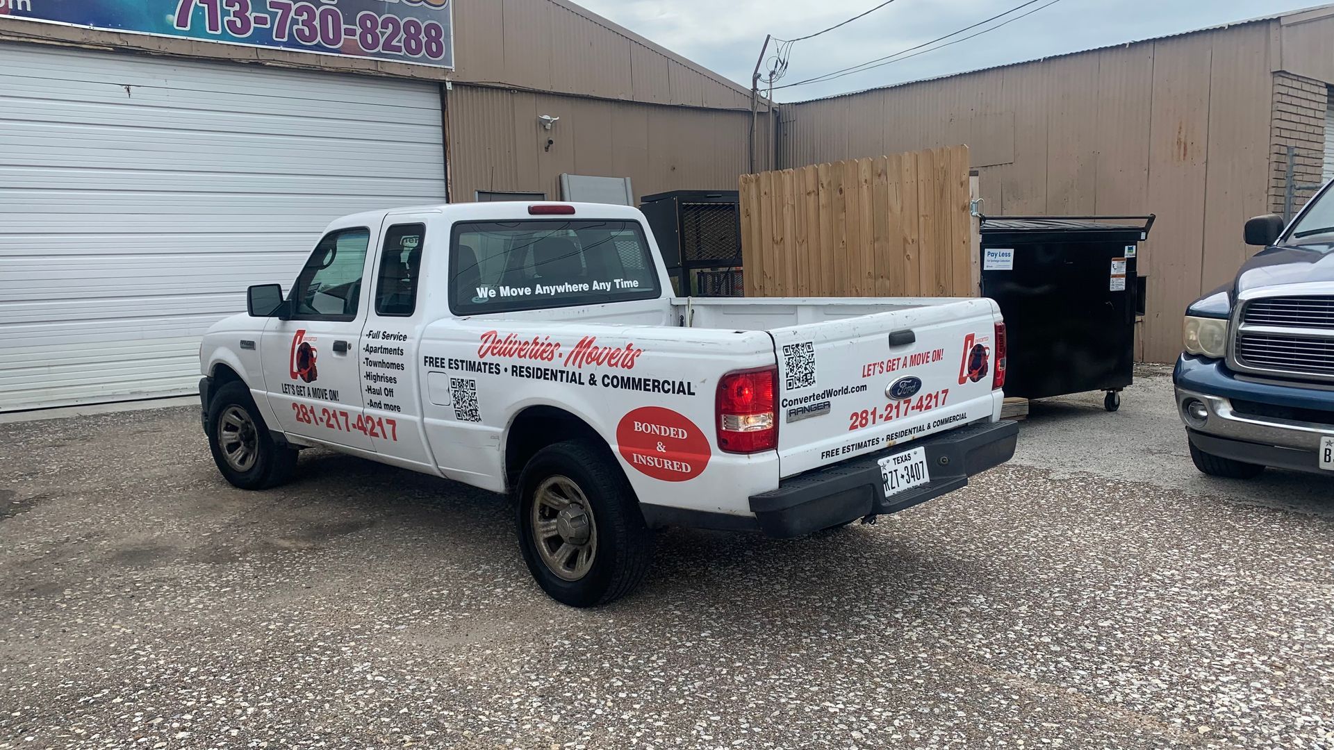 White Ford Ranger pickup truck with business logos parked on gravel.