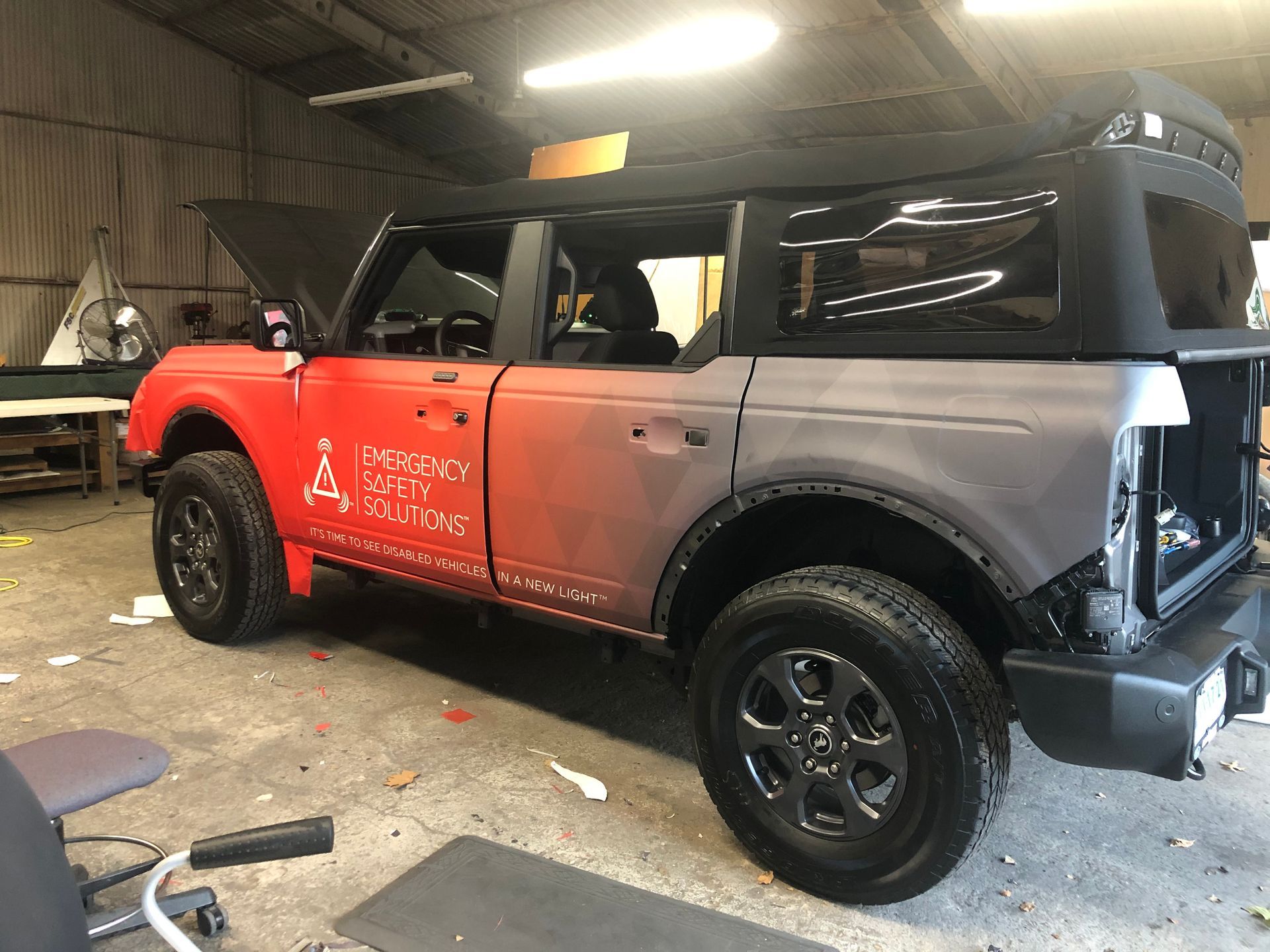 Red and gray Ford Bronco being worked on in a garage.  