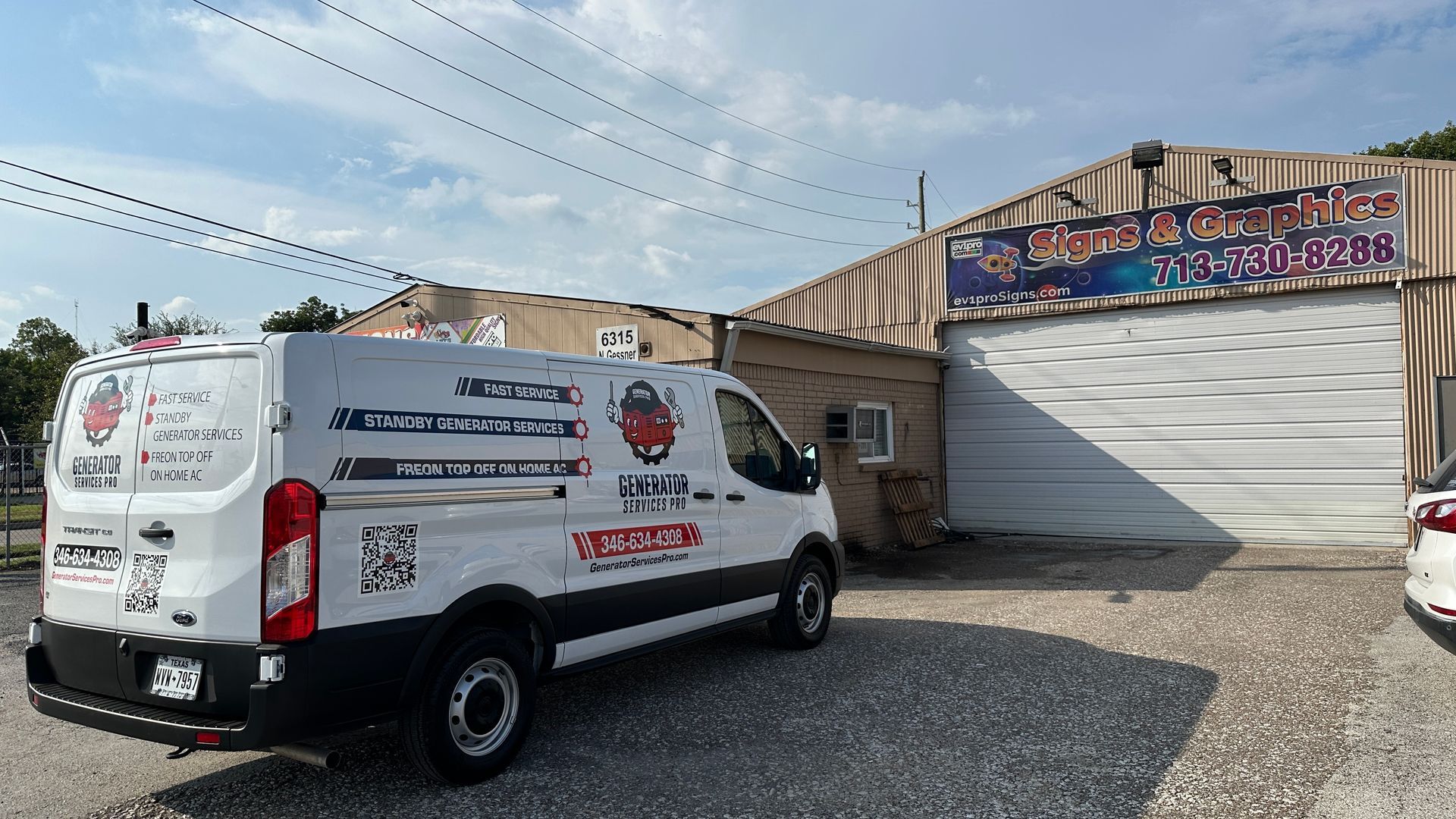 White service van parked outside a building with a business sign; sunny day.