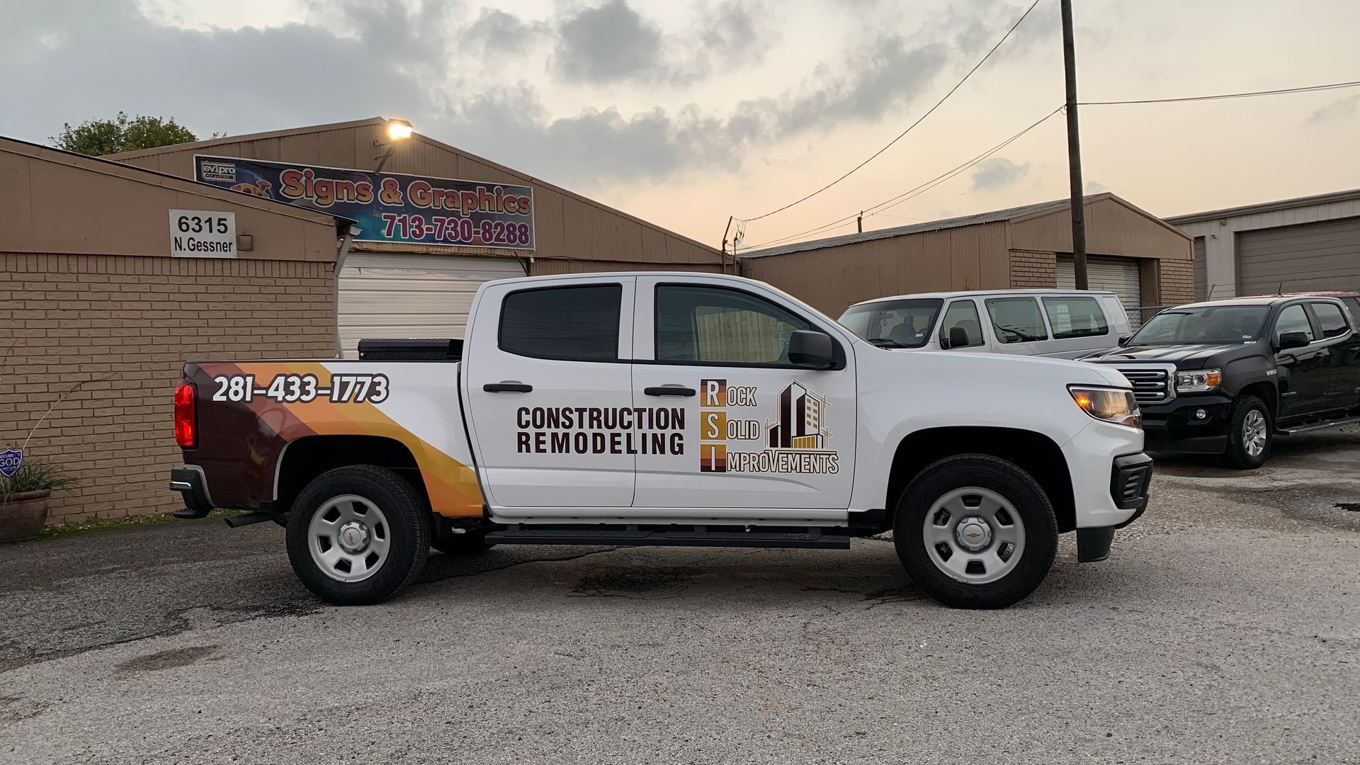 White pickup truck with company logo parked outside a building.
