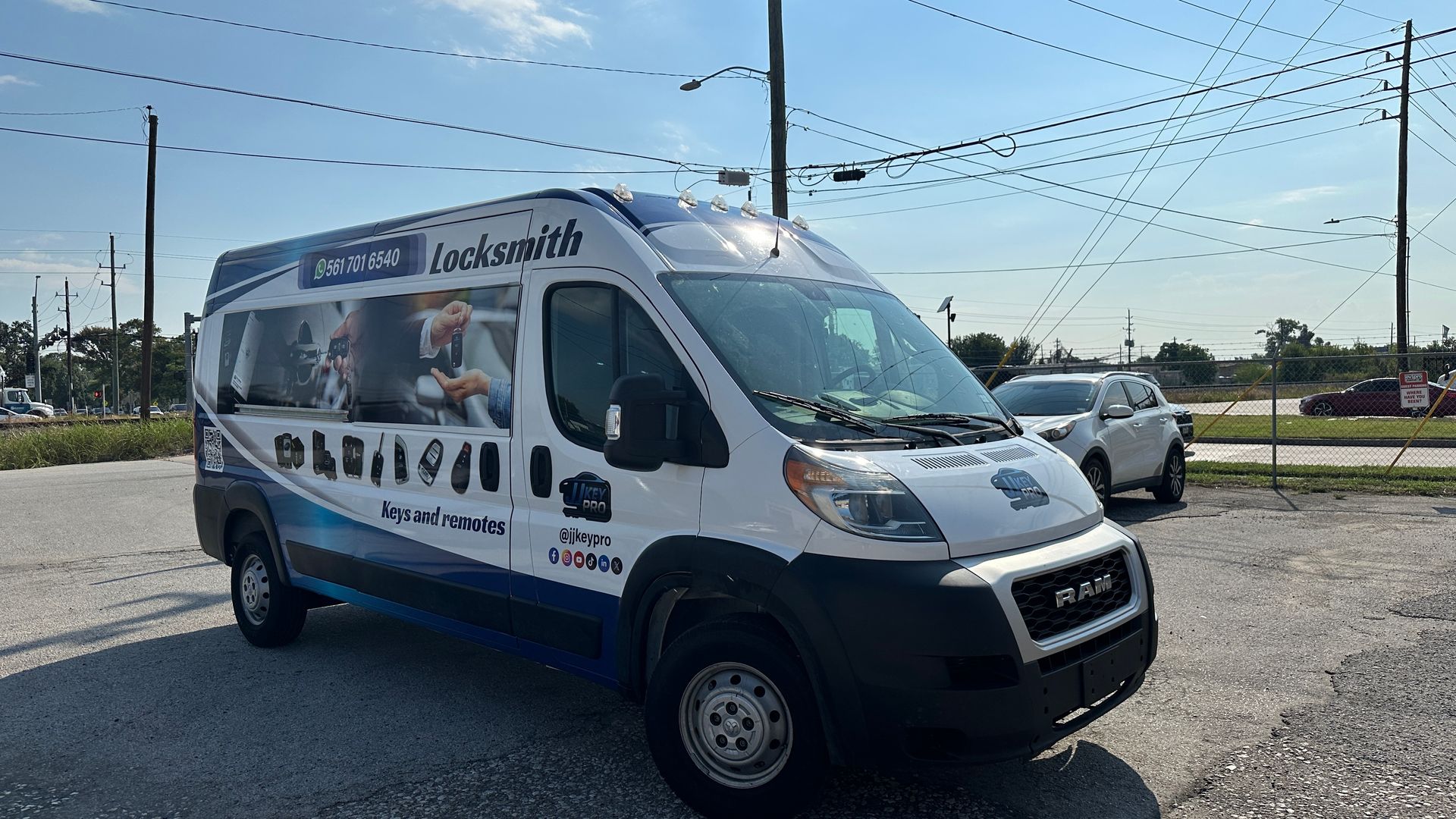 White and blue service van parked outdoors, sunny day. Van has logos and images on the side.