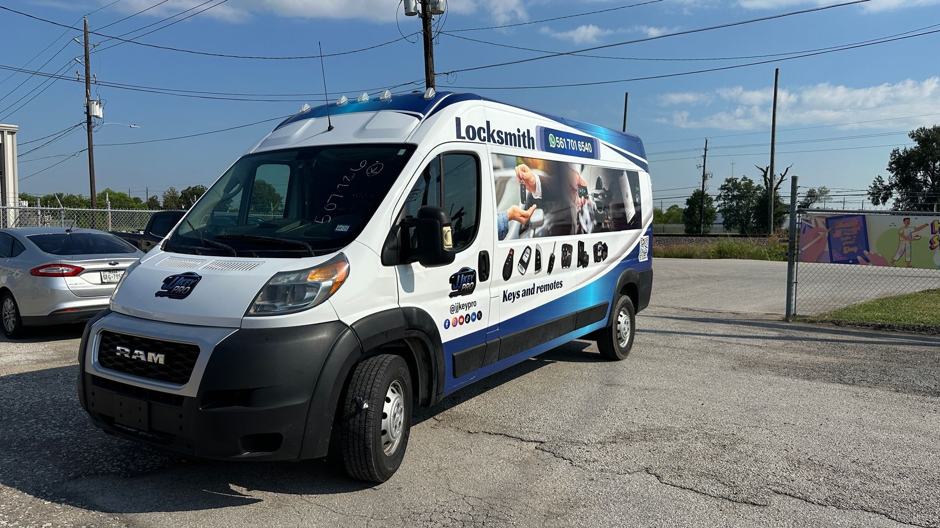 White locksmith van with blue accents parked on gravel lot.