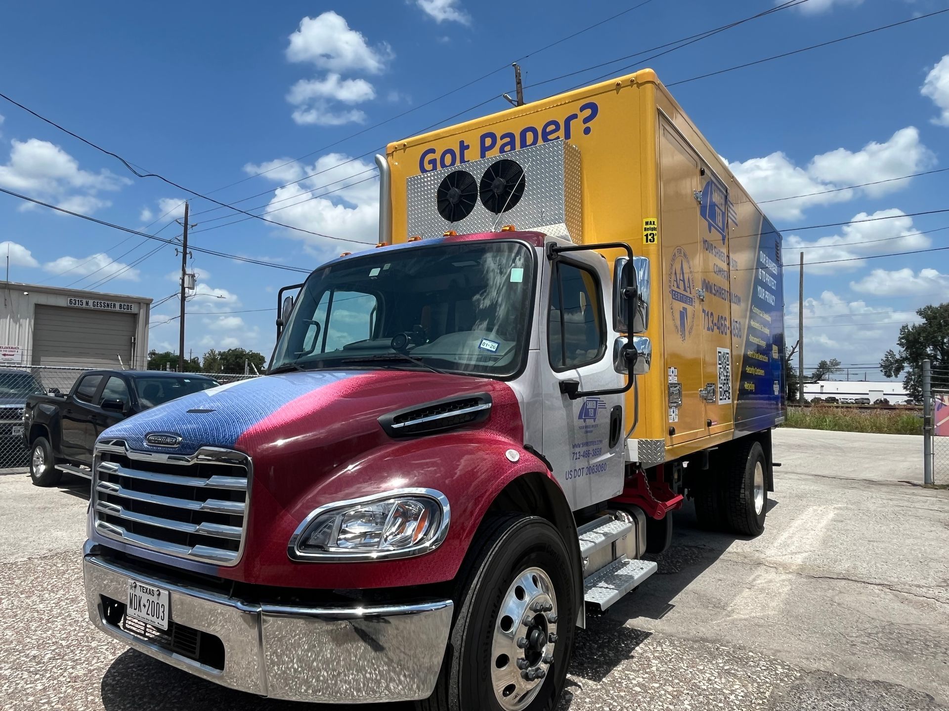Recycling truck with blue, red, and yellow paint, parked on a sunny day. 