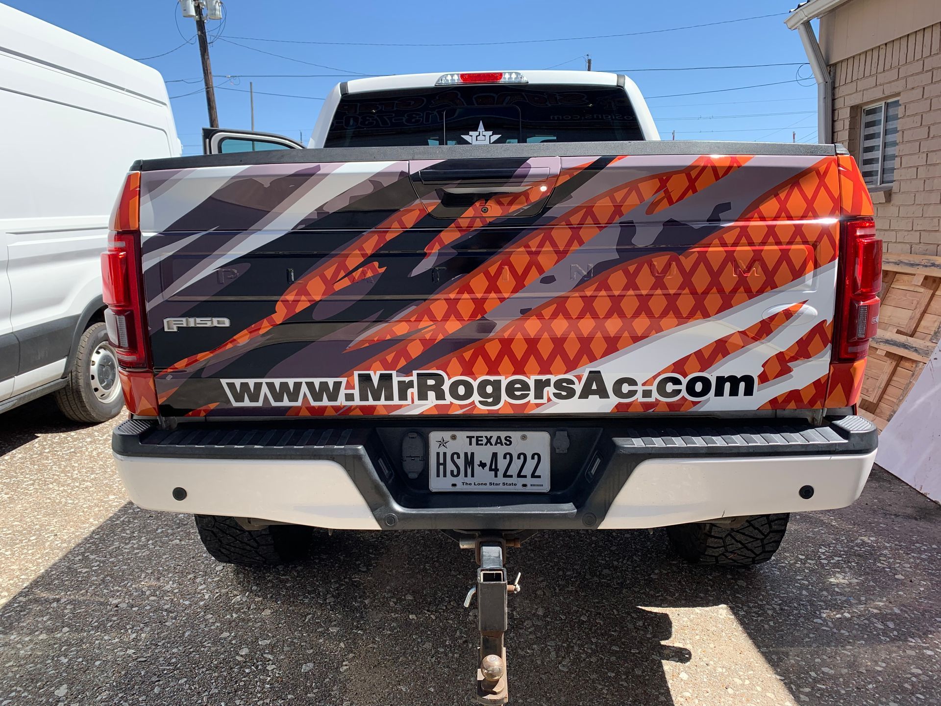Rear view of a white pickup truck with custom orange and black design advertising Mr. Rogers AC.  Texas license plate.