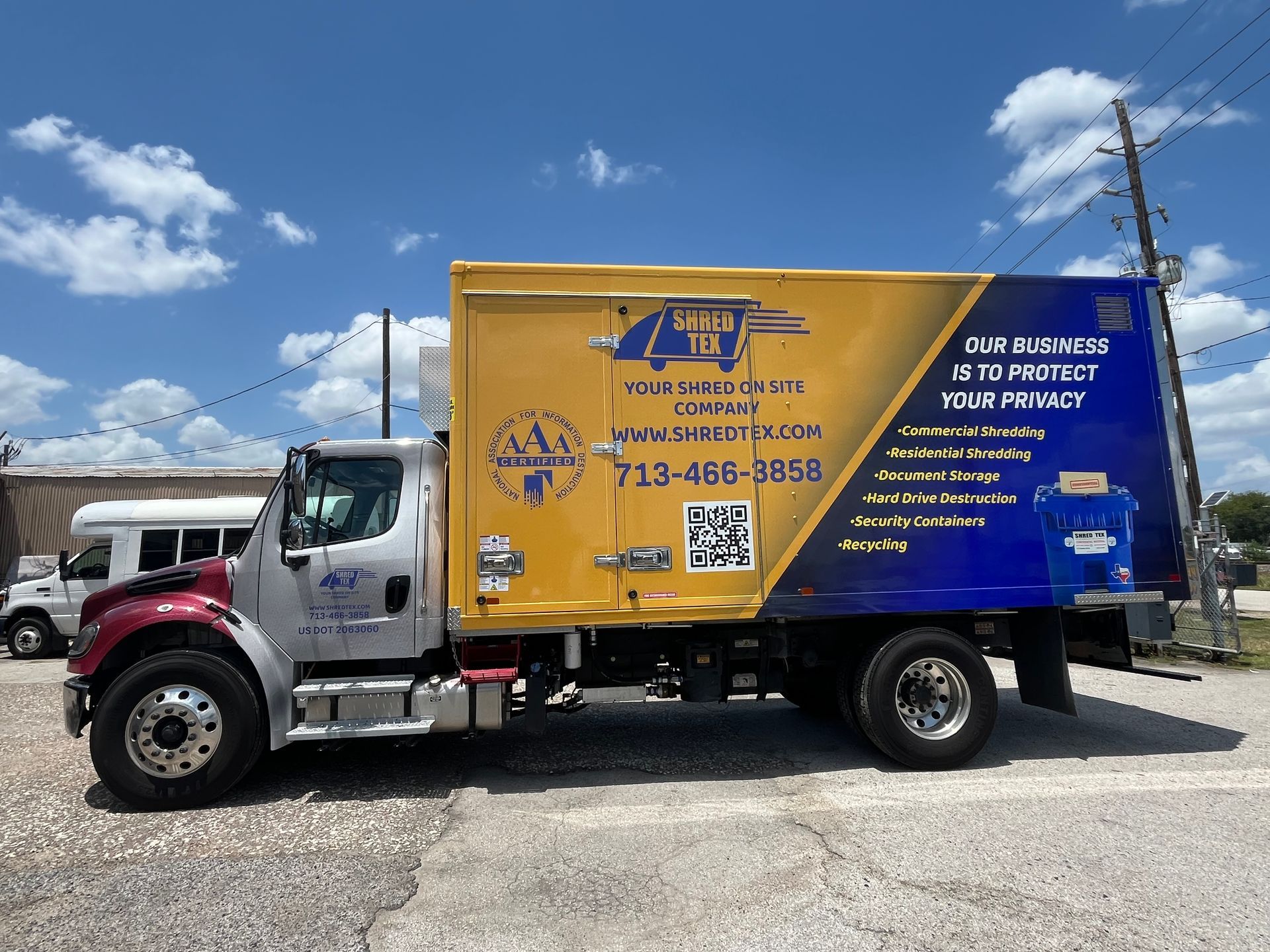 Yellow and blue box truck with company logo, parked on a paved lot on a sunny day.