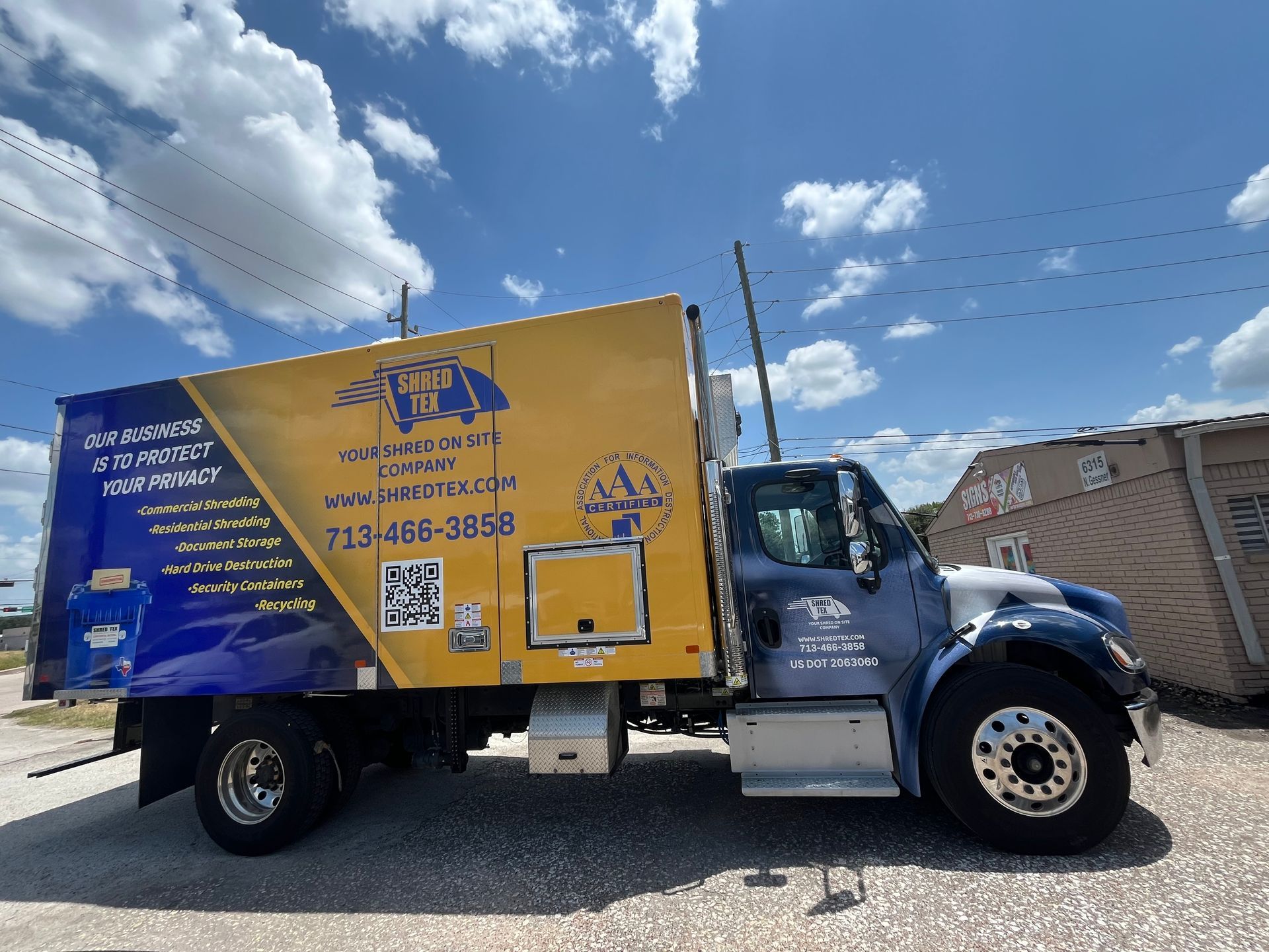 Yellow and blue service truck on a sunny day with a blue sky.