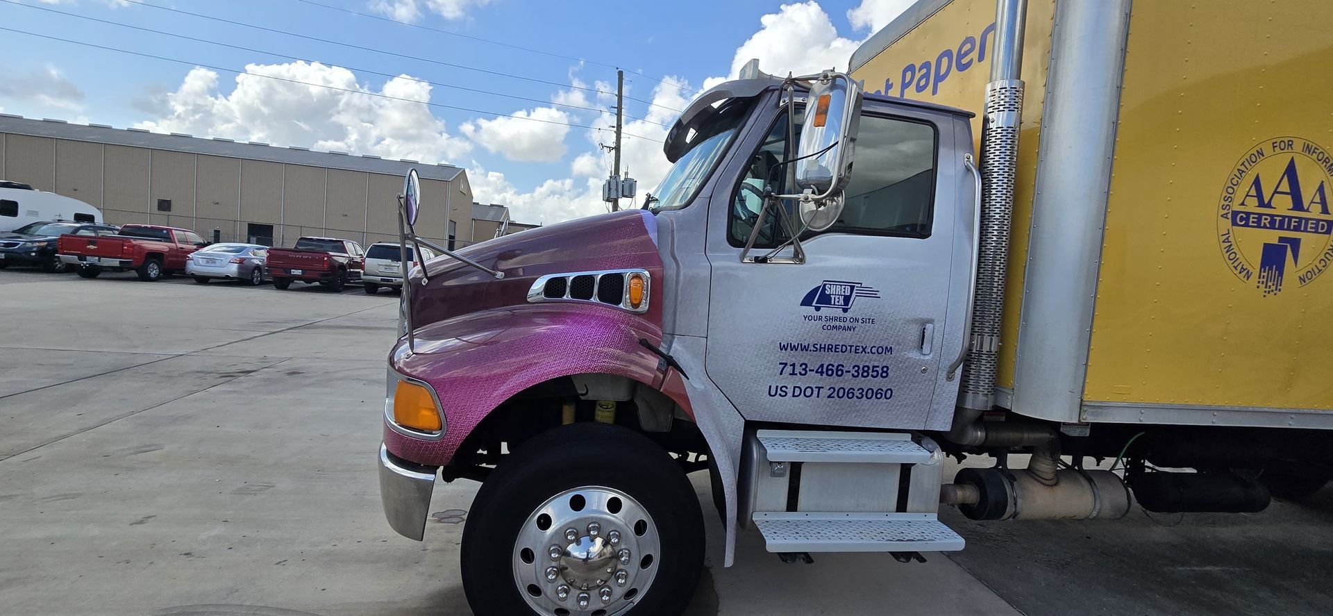 A maroon and white truck with a yellow trailer parked outside.