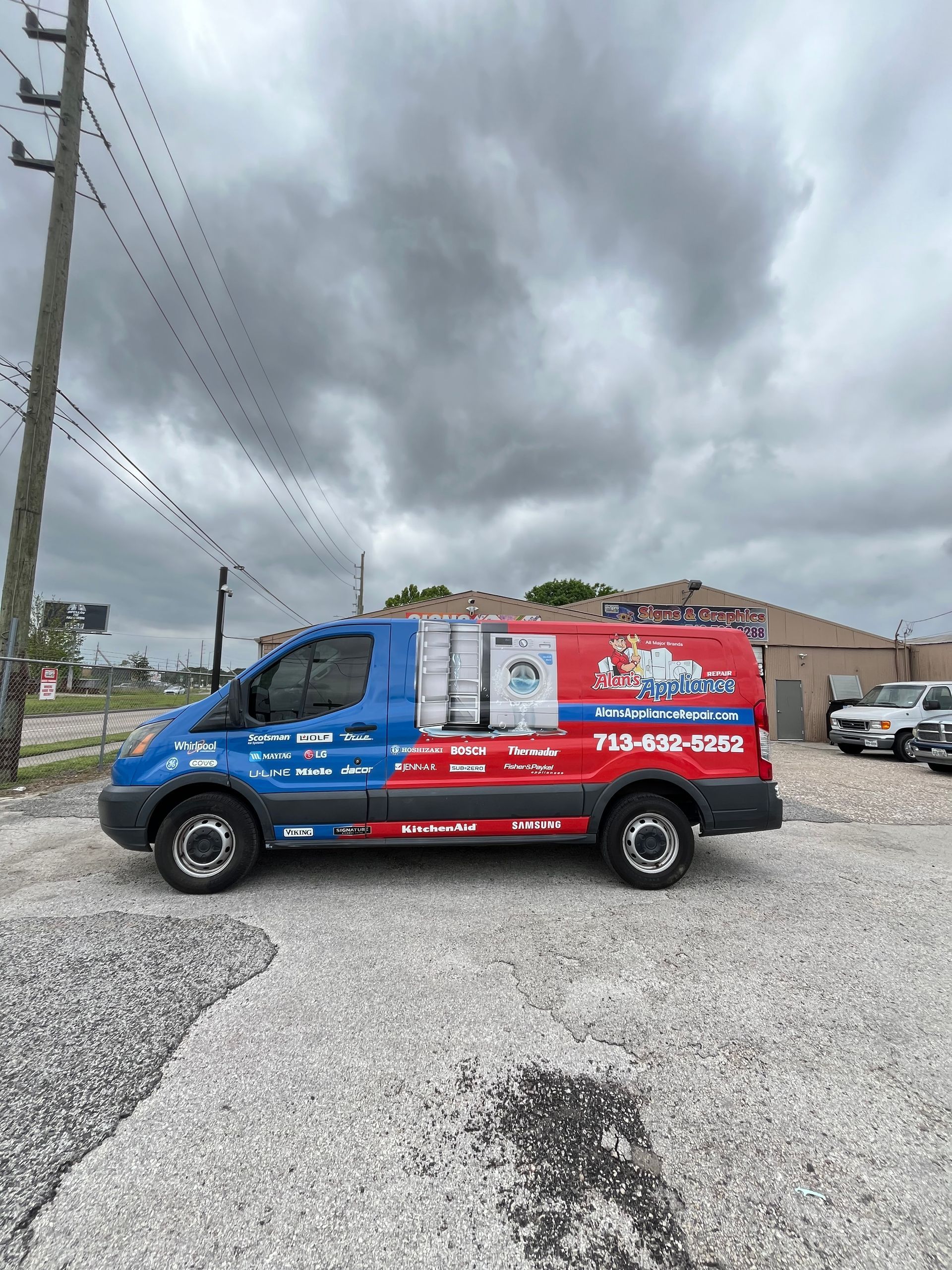 Blue and red service van parked on gravel, cloudy sky in background.  Van has business logo and phone number.