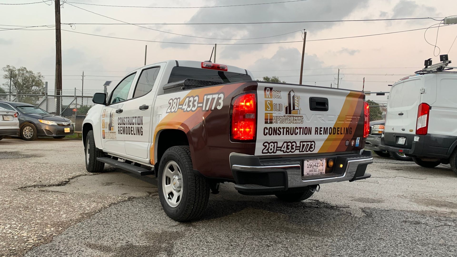 White pickup truck with company logo parked on gravel, overcast day.