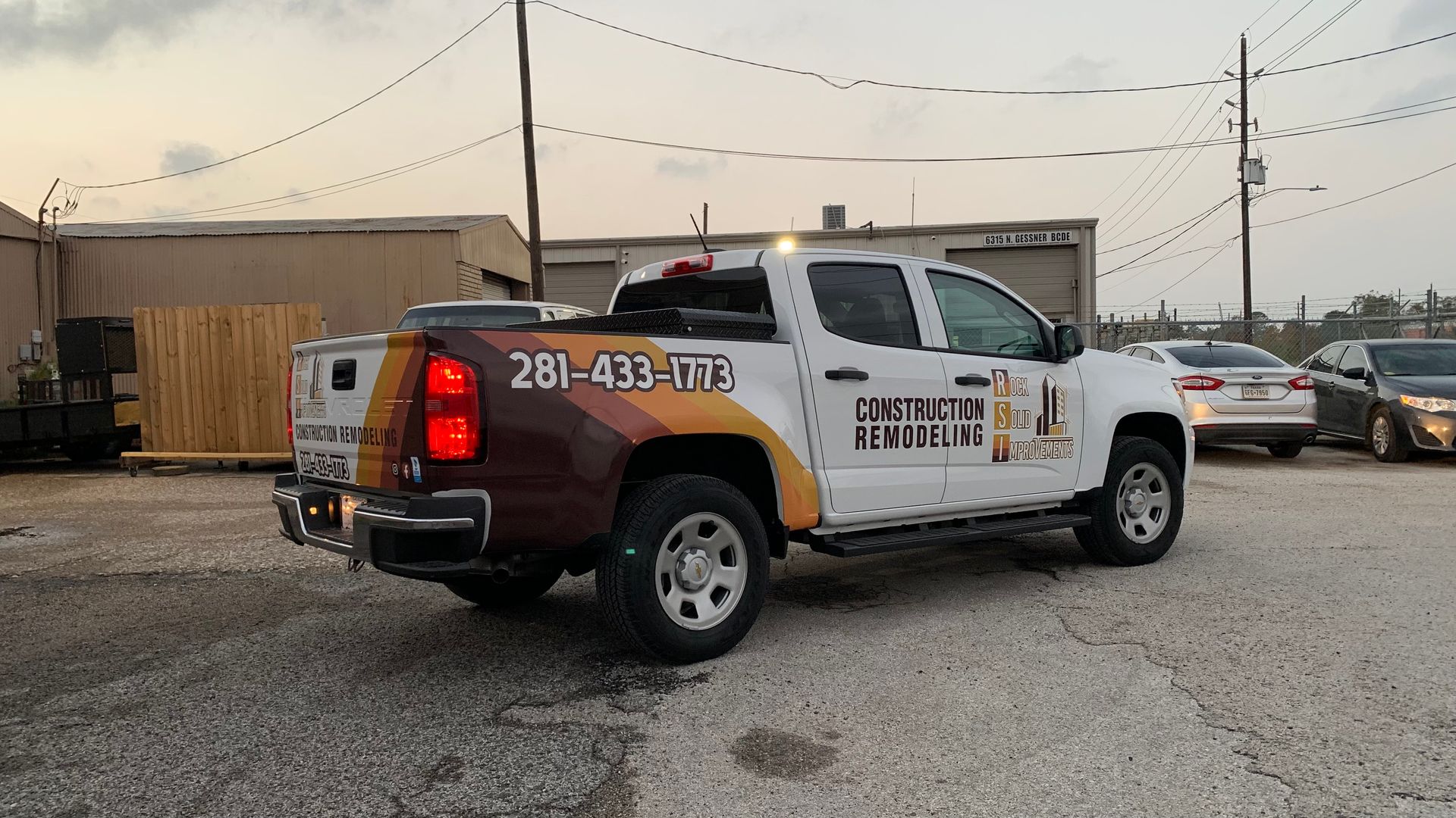 White Chevy pickup truck with company logo and phone number parked outdoors.