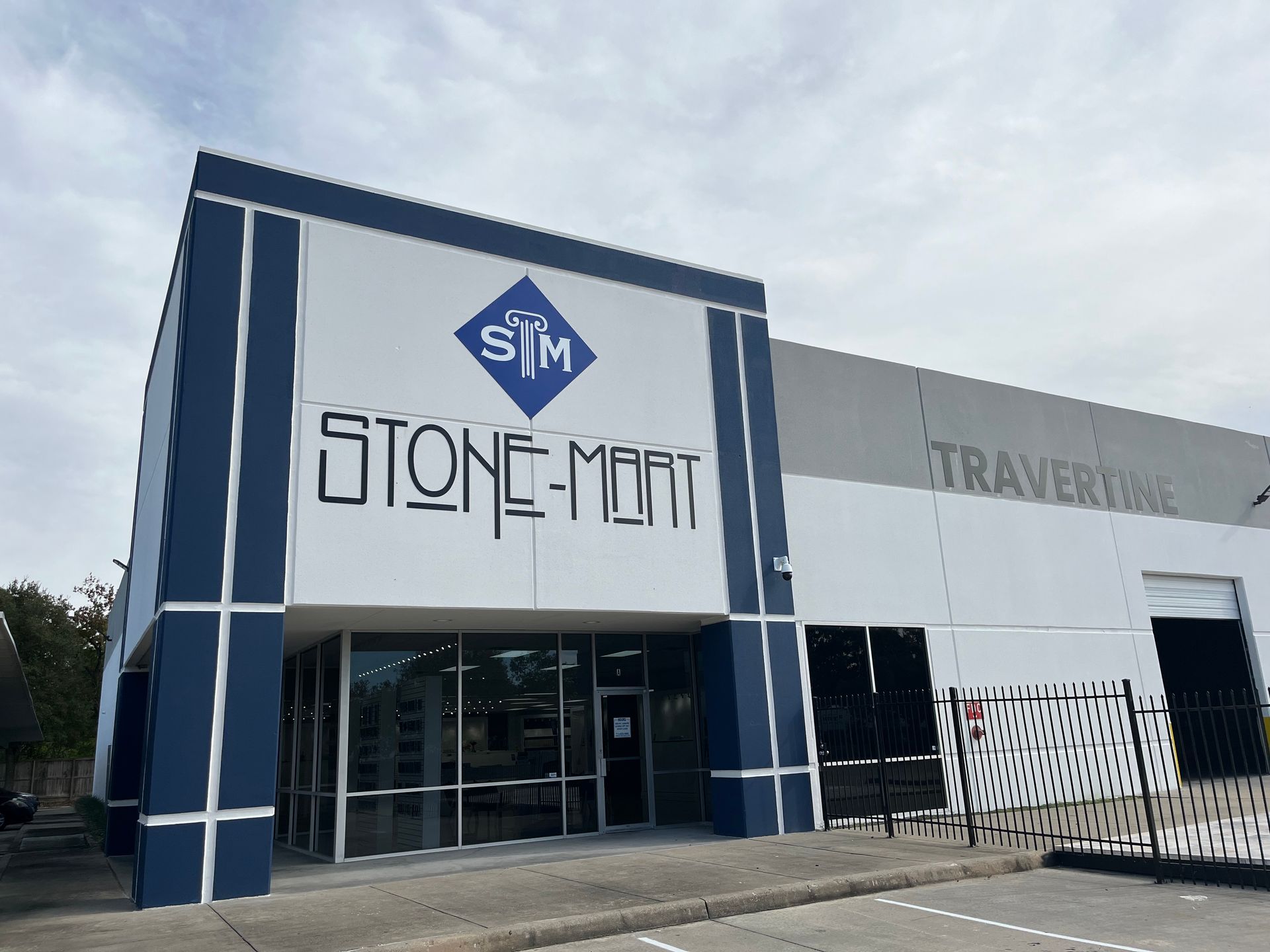 Stone-Mart building with blue and white exterior, store name above the entrance. Cloudy sky.