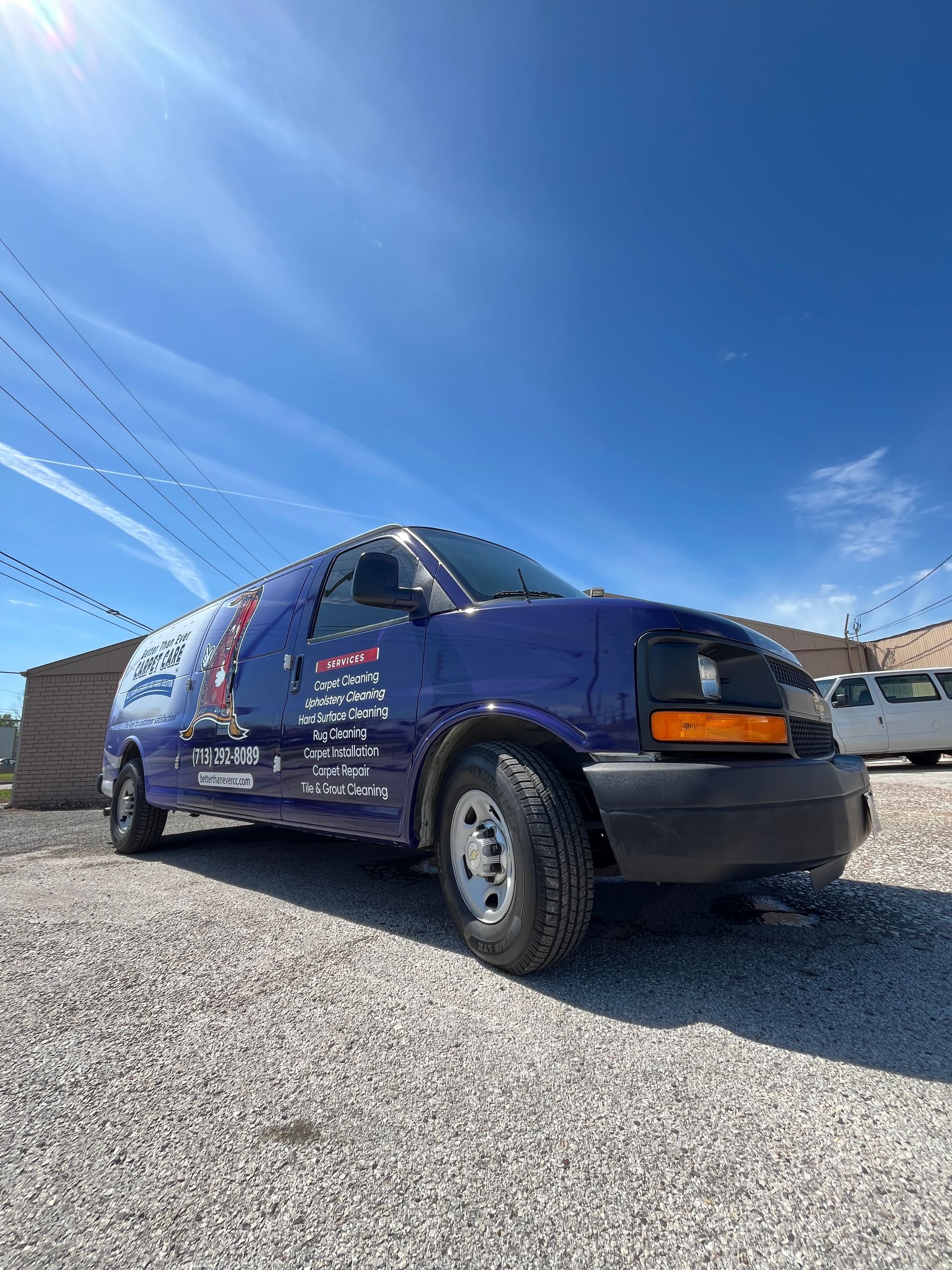 Blue service van parked on gravel under a blue sky, with advertising on its side.