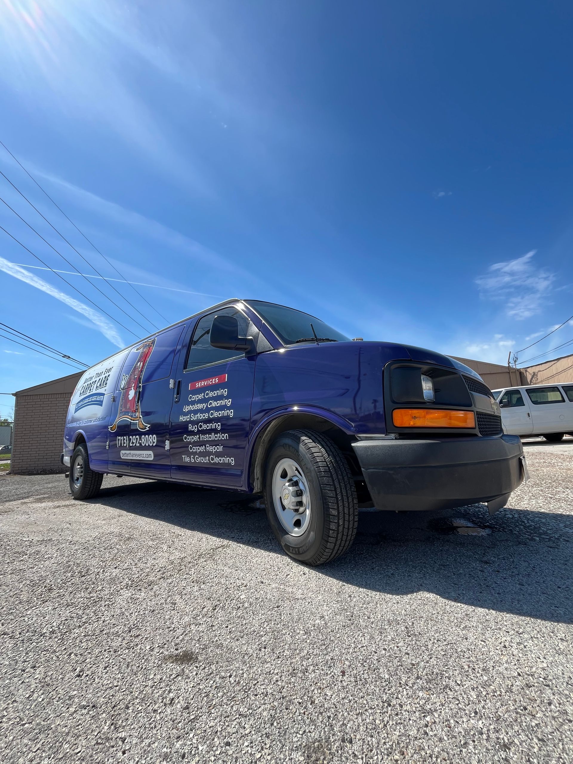 Blue service van parked on gravel under a blue sky, with business logos on its side.