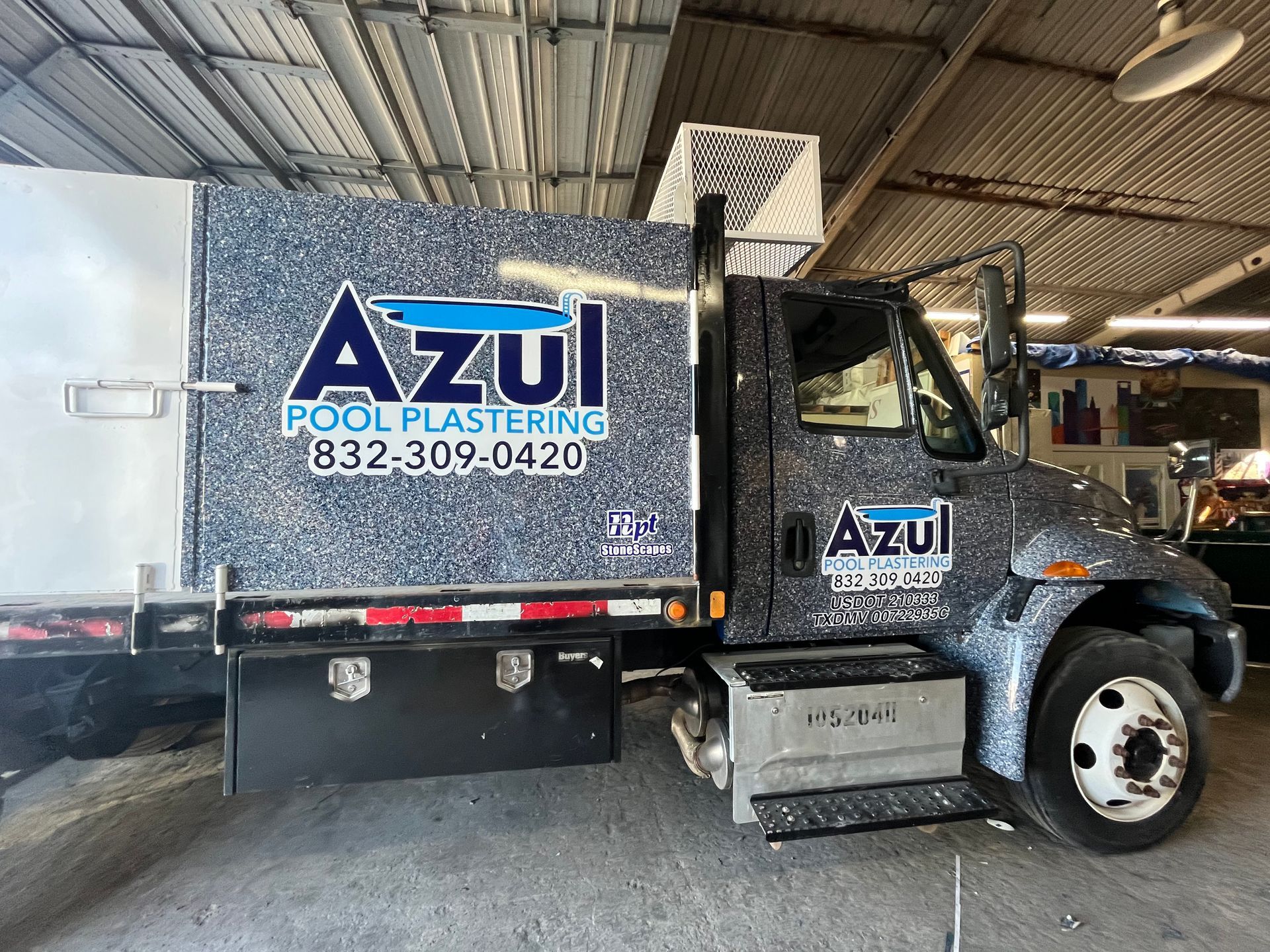 Azul Pool Plastering truck with blue speckled design and company logo; parked indoors.
