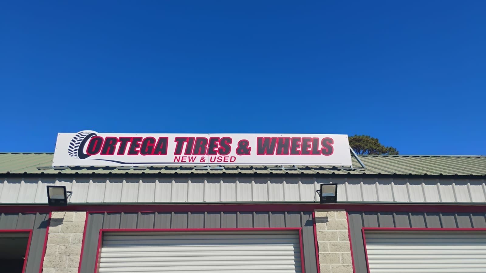 Sign for Ortega Tires & Wheels on a building with a blue sky background.