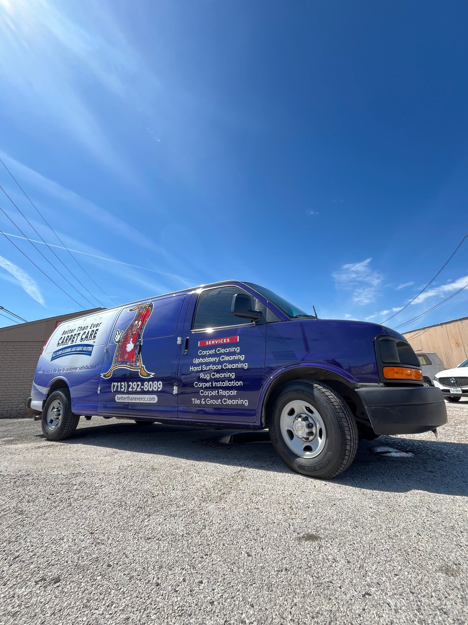 Blue commercial van parked on gravel under a blue sky with company logos.