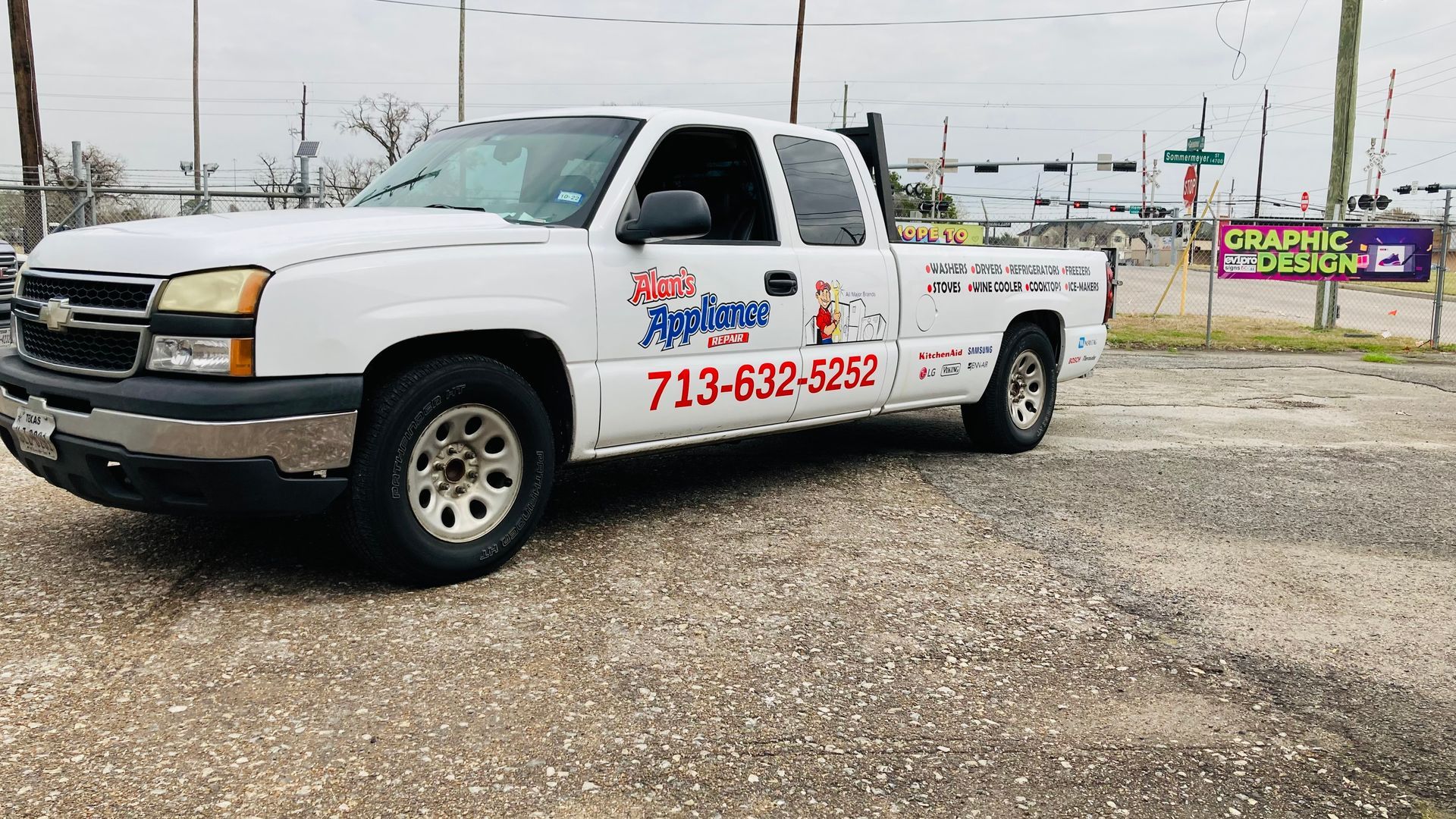 White pickup truck with business logo on the side, parked in a lot.