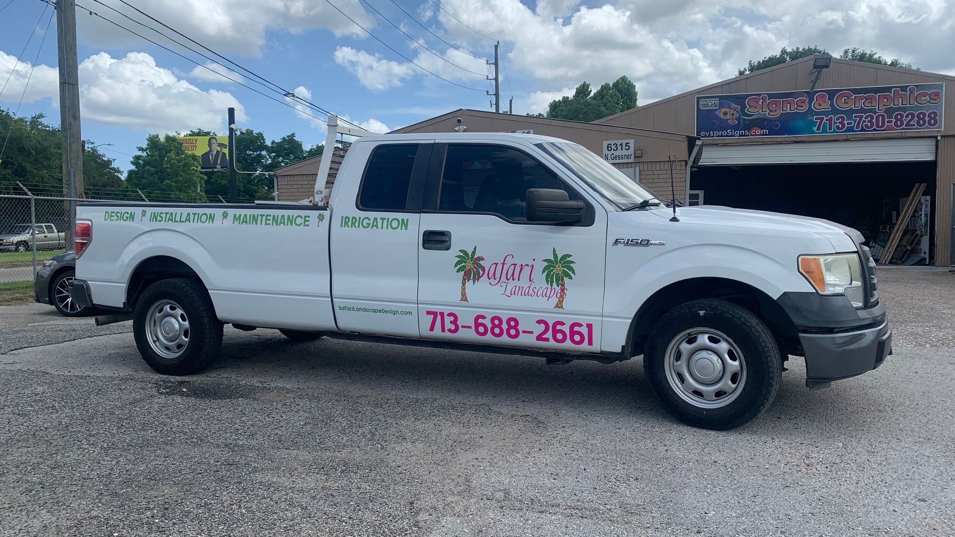 White pickup truck with business signage and phone number parked on gravel.
