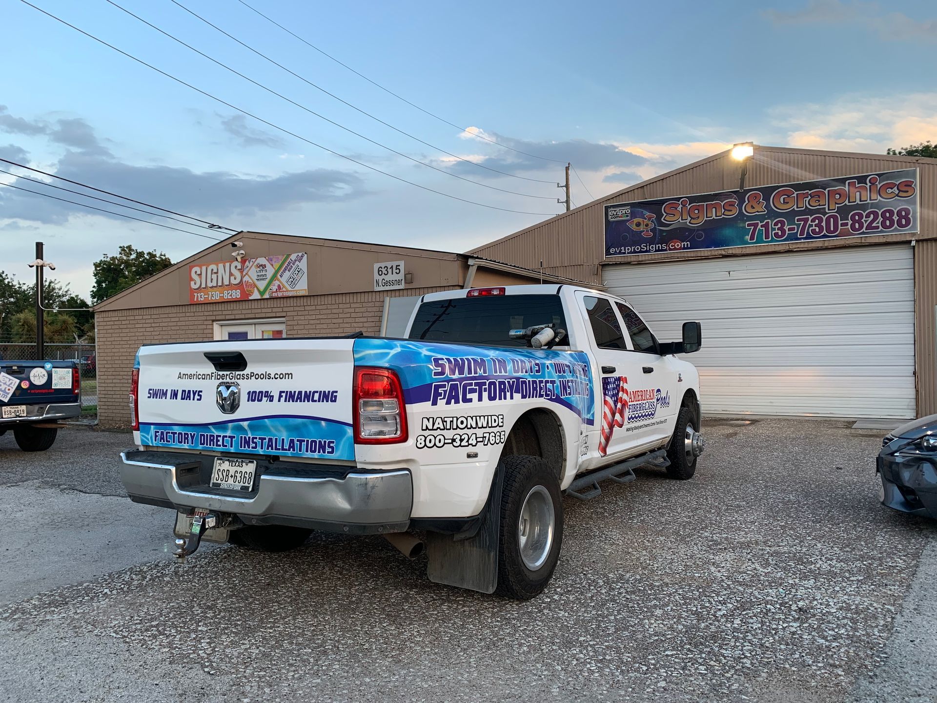 White pickup truck with business signage parked in front of a building.