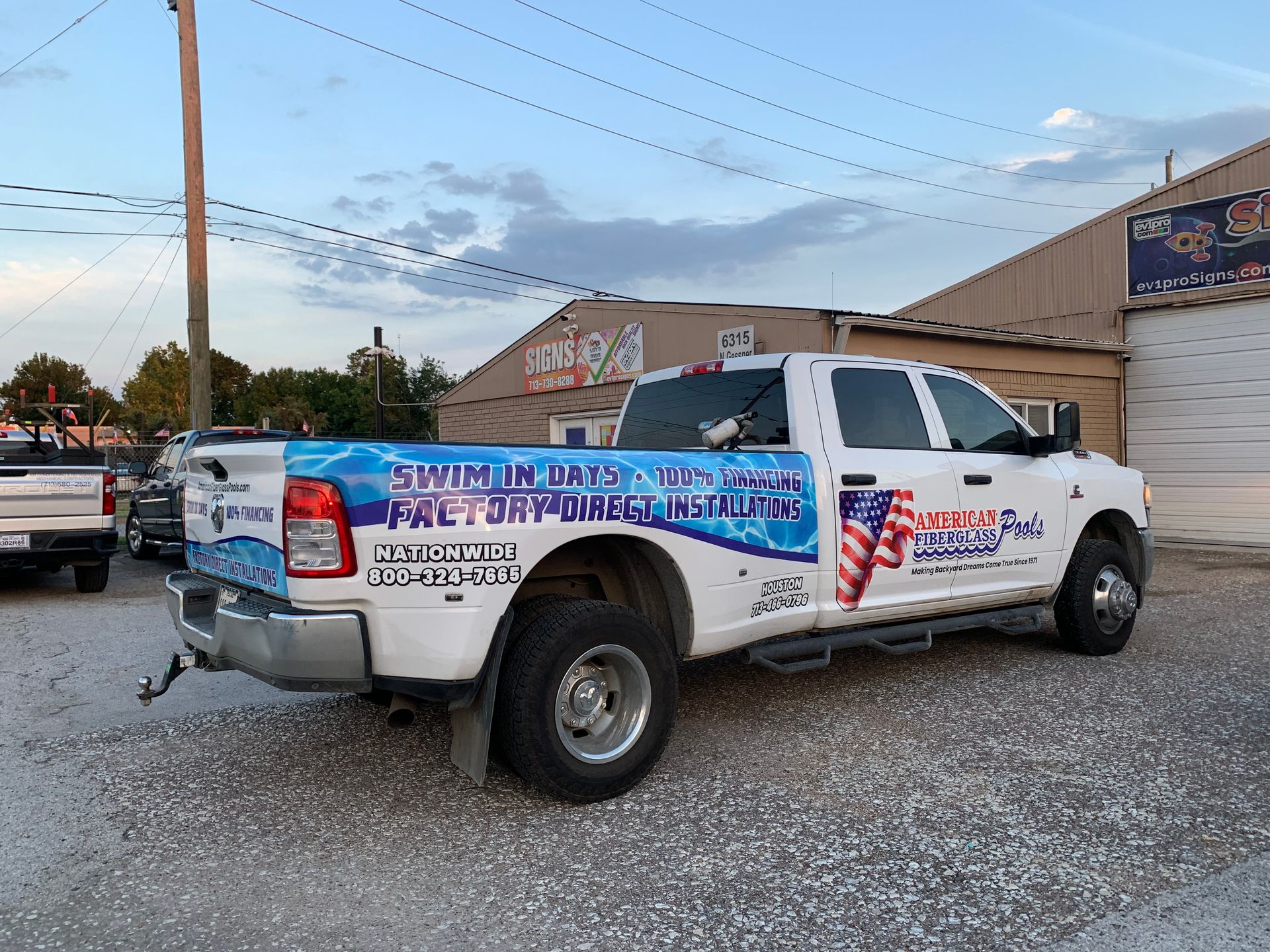 White truck with blue graphics parked outside a building. 