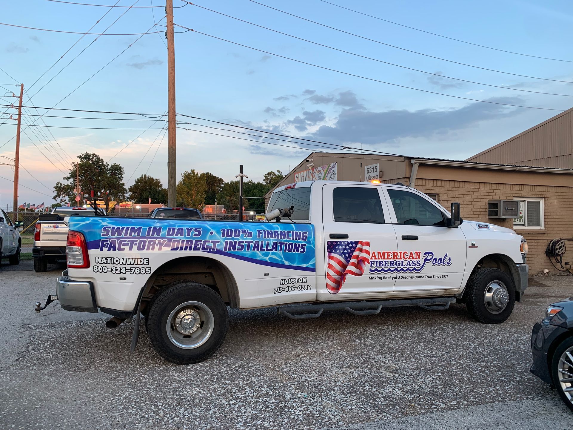 White pickup truck with blue and white side graphics advertising a pool service, parked outdoors.