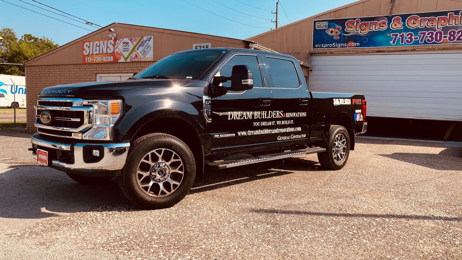 Black Ford truck parked in front of a business with signs.