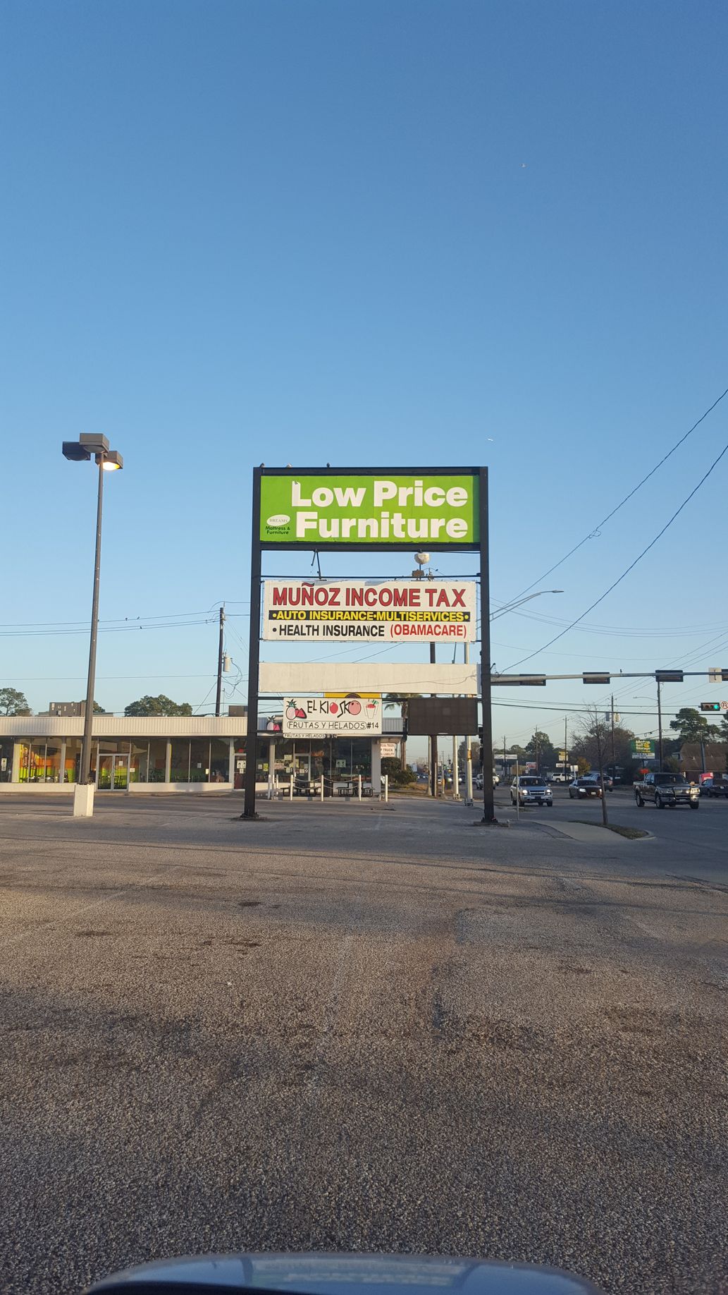 Sign for Low Price Furniture and other businesses, with a blue sky background.