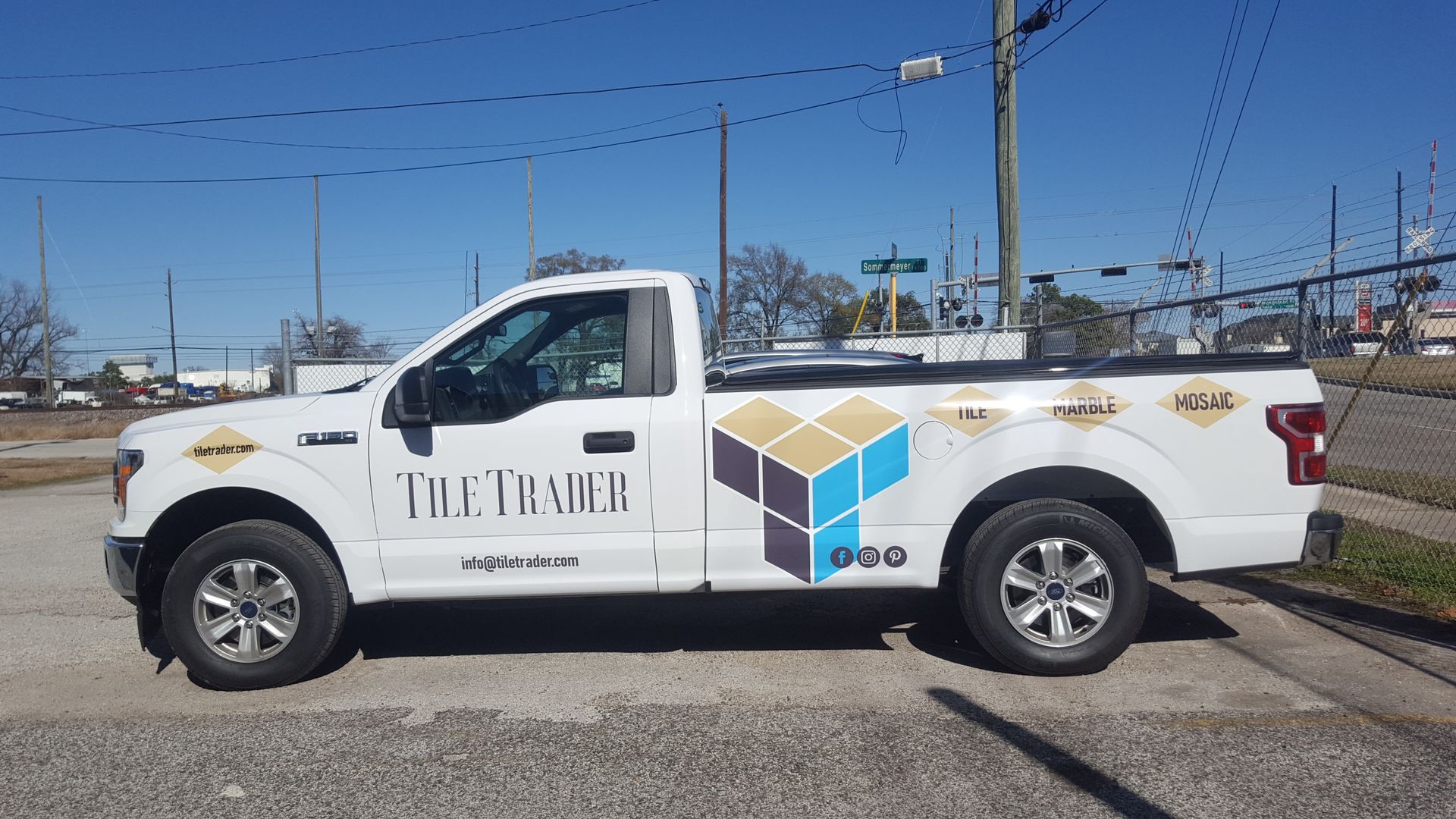 White pickup truck with company logo parked on a street. 
