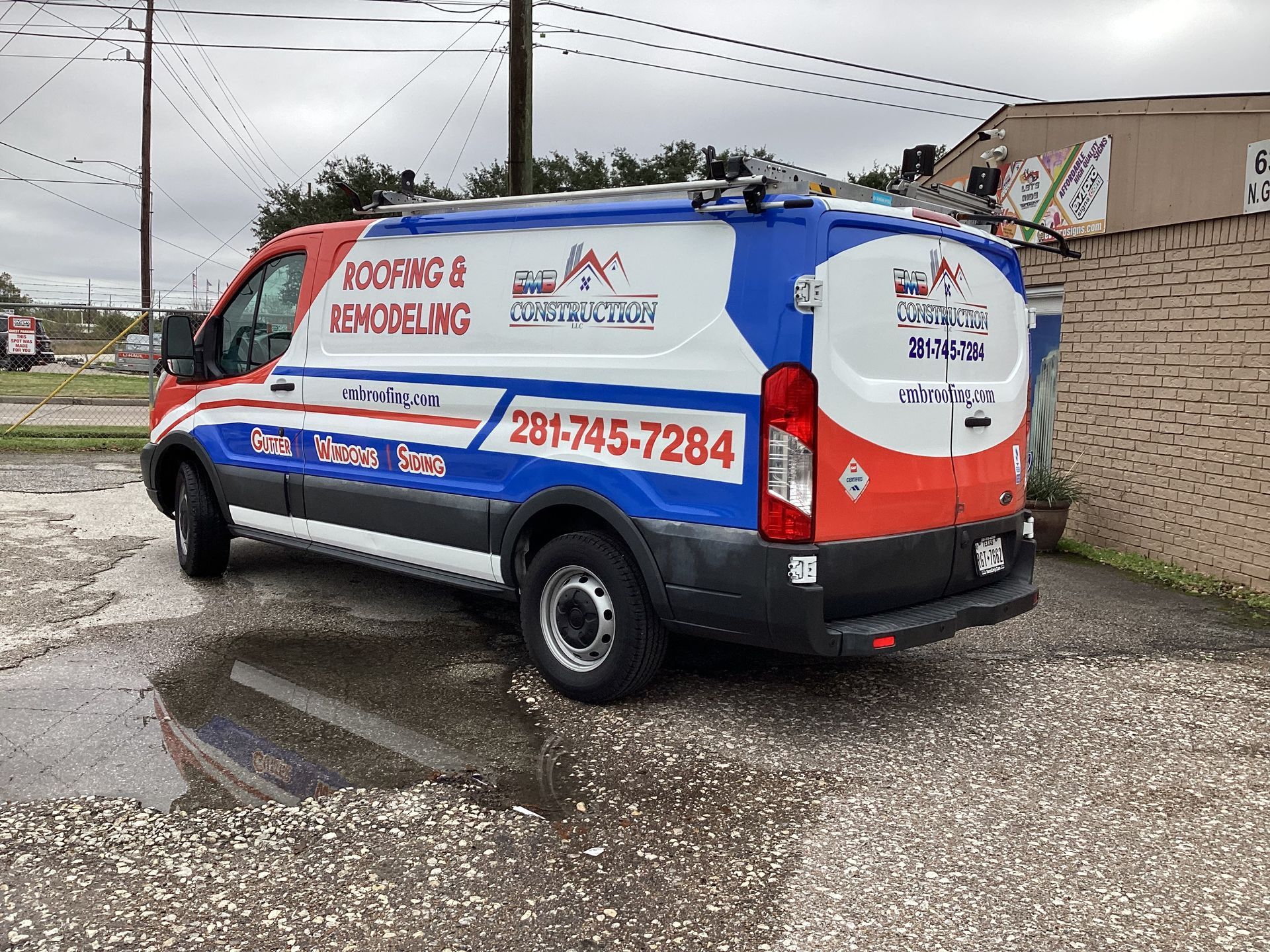 Roofing and remodeling company van with a Texas flag design, parked outdoors. Phone number 281-745-7284.