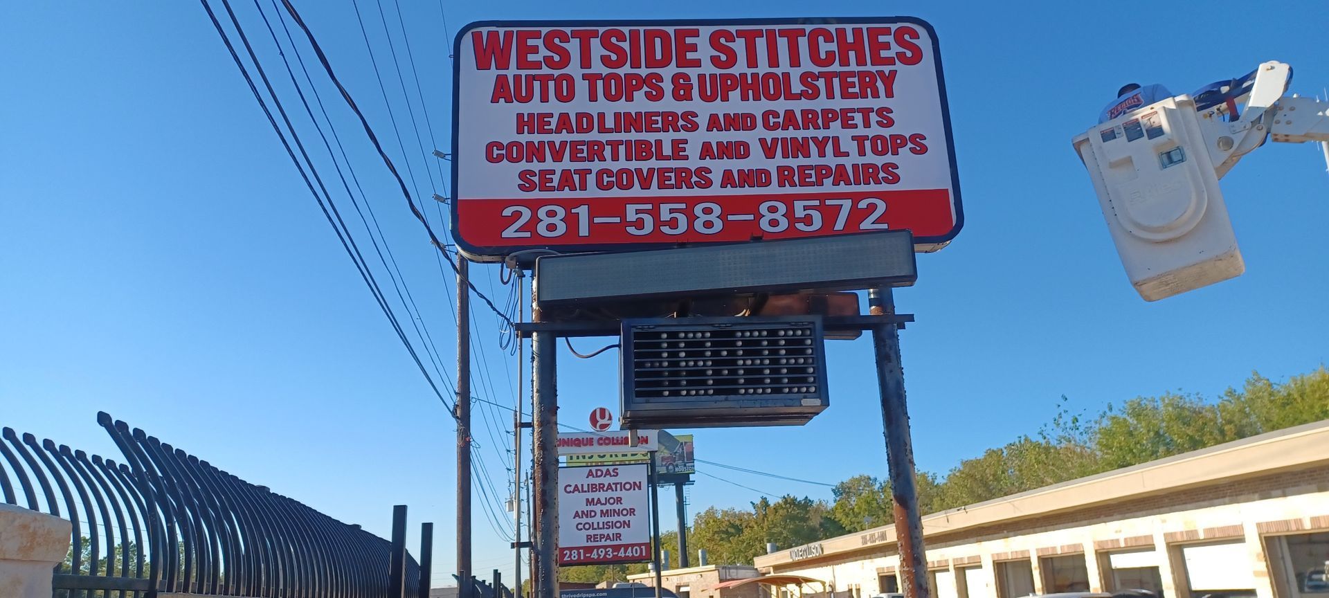 Sign for West Side Stitches. It provides auto tops, upholstery, and seat cover services. Has phone number 281-558-8572.