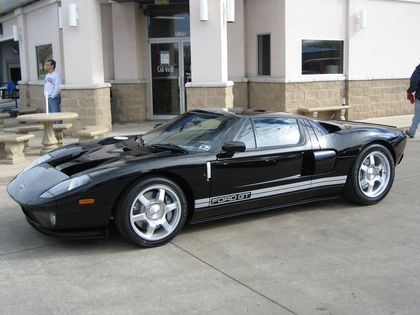 A black sports car is parked in front of a building that says life