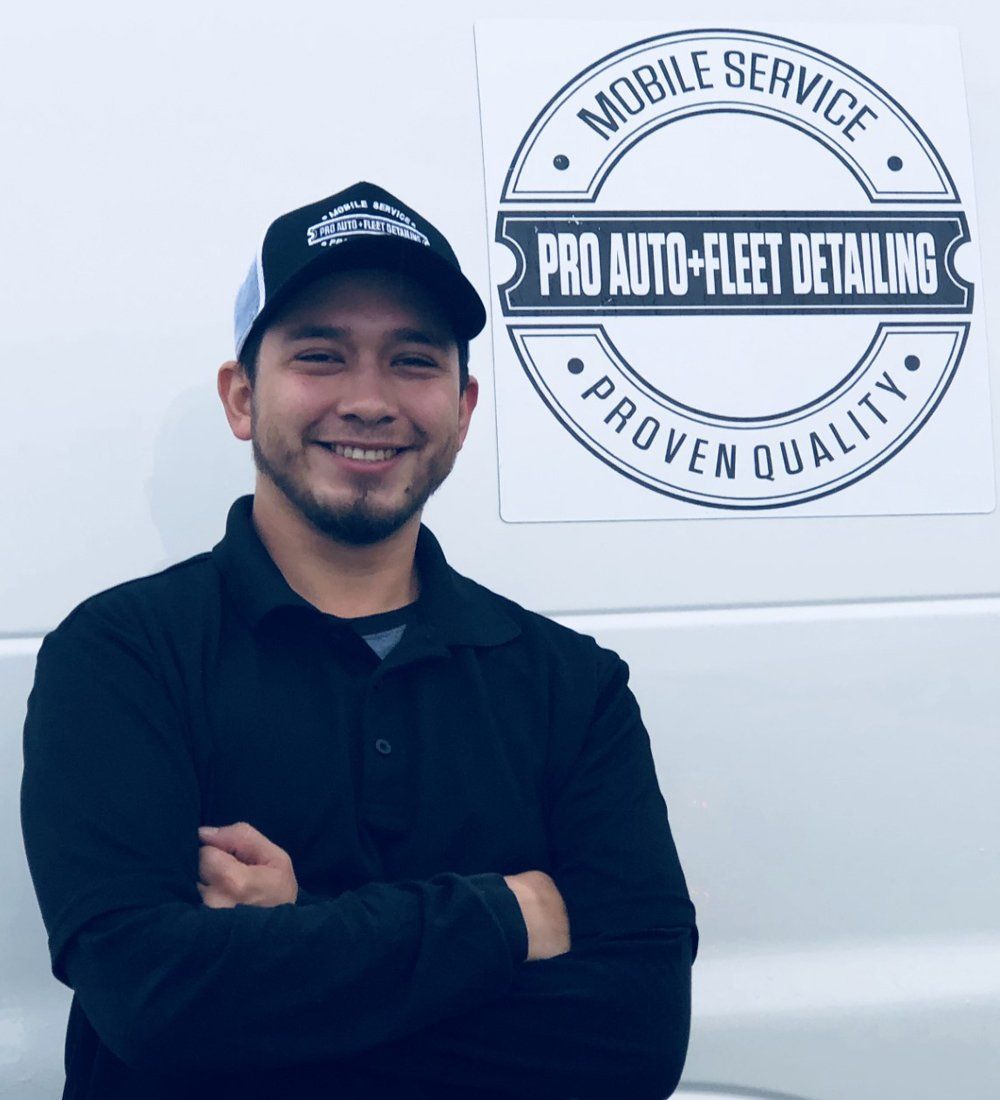 A man standing in front of a pro auto fleet detailing sign