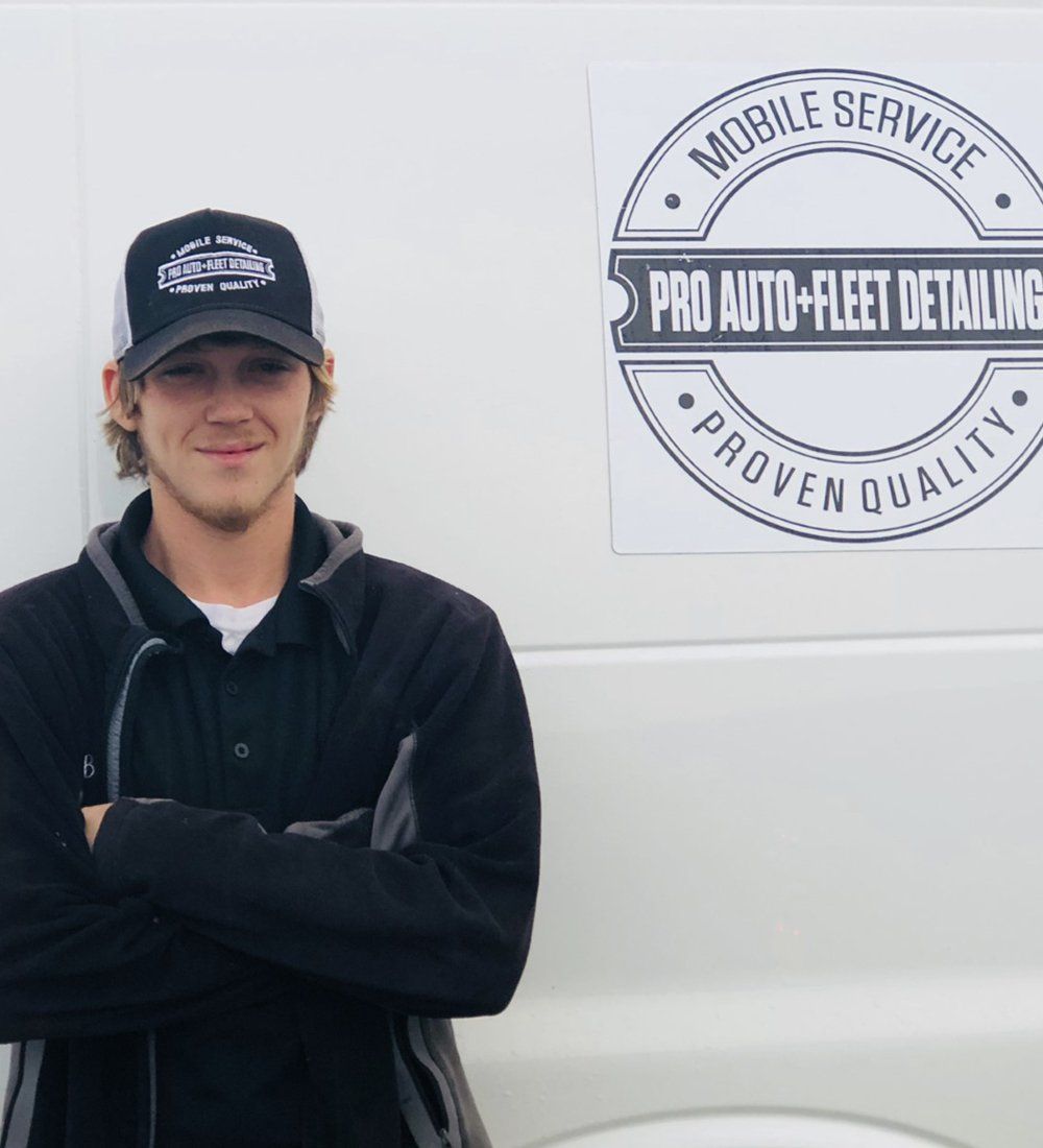 A man standing in front of a pro auto fleet detailing sign