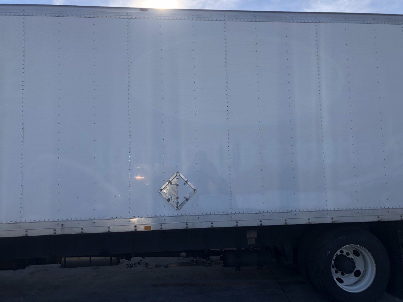 A white truck with a diamond on the side is parked in a parking lot.