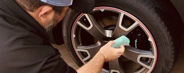 man cleaning tires of an auto