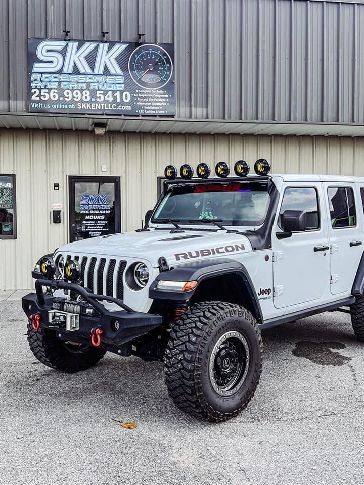 A white jeep is parked in front of a building.