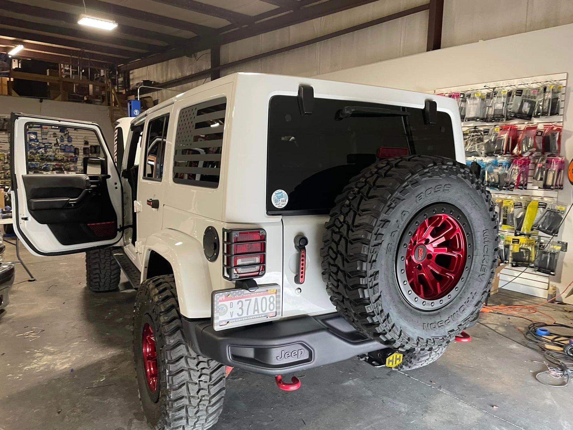 A white jeep with red wheels is parked in a garage.