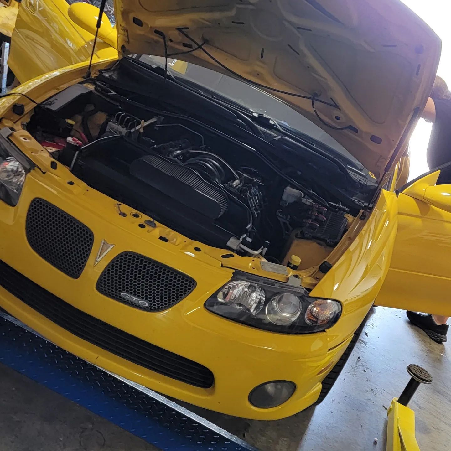 A yellow pontiac gto with the hood open