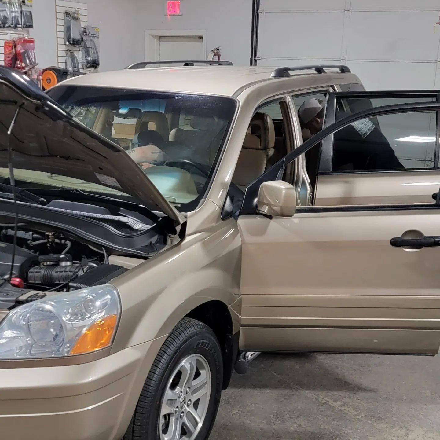 A car with the hood up is parked in a garage