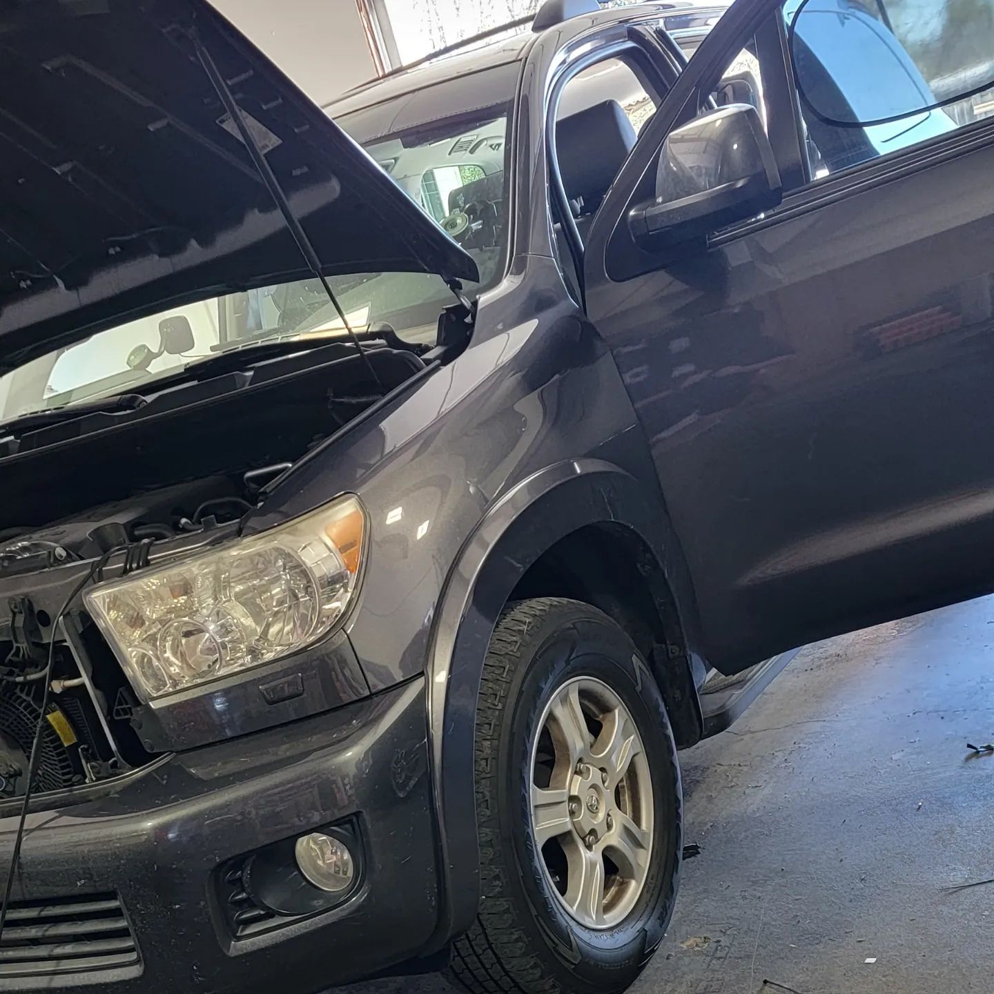 A black truck with the hood open is parked in a garage.