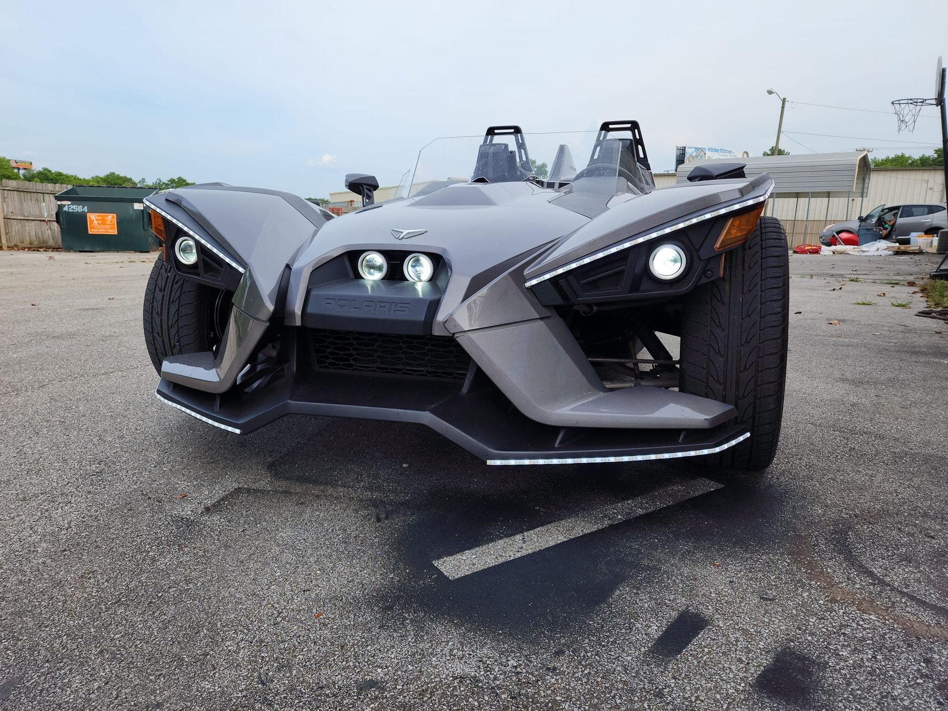 A slingshot is parked in a parking lot.