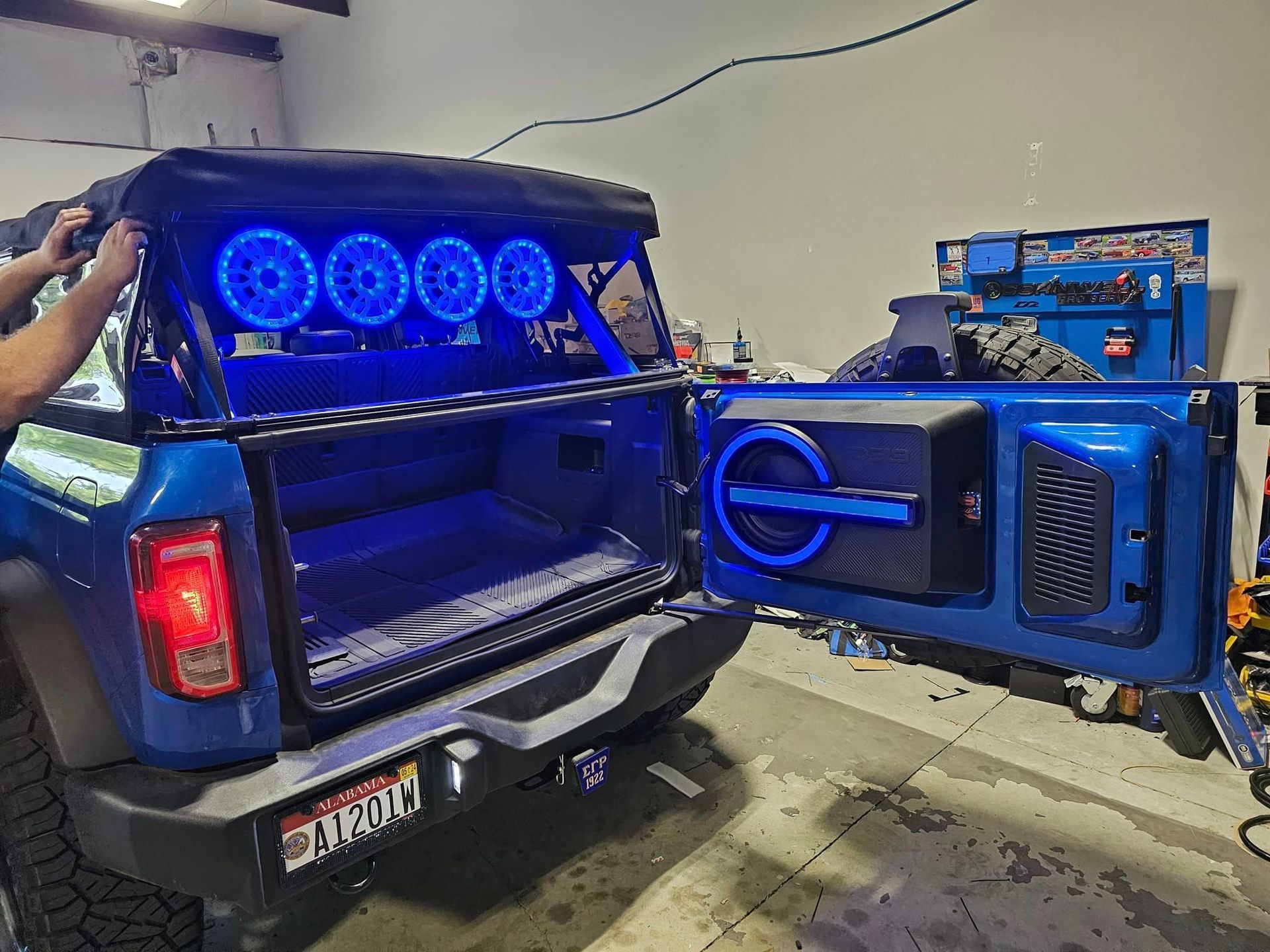 A man is working on the trunk of a blue truck.