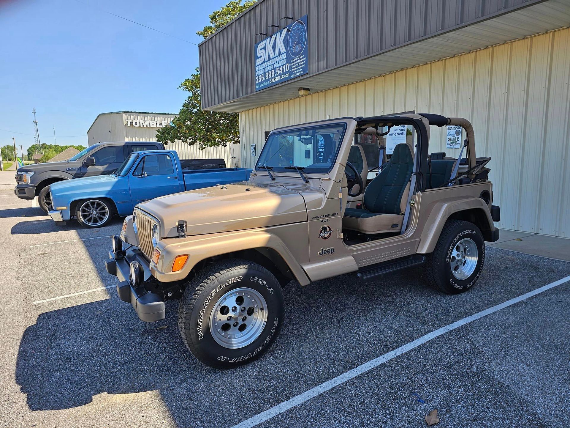 A jeep is parked in a parking lot in front of a building.