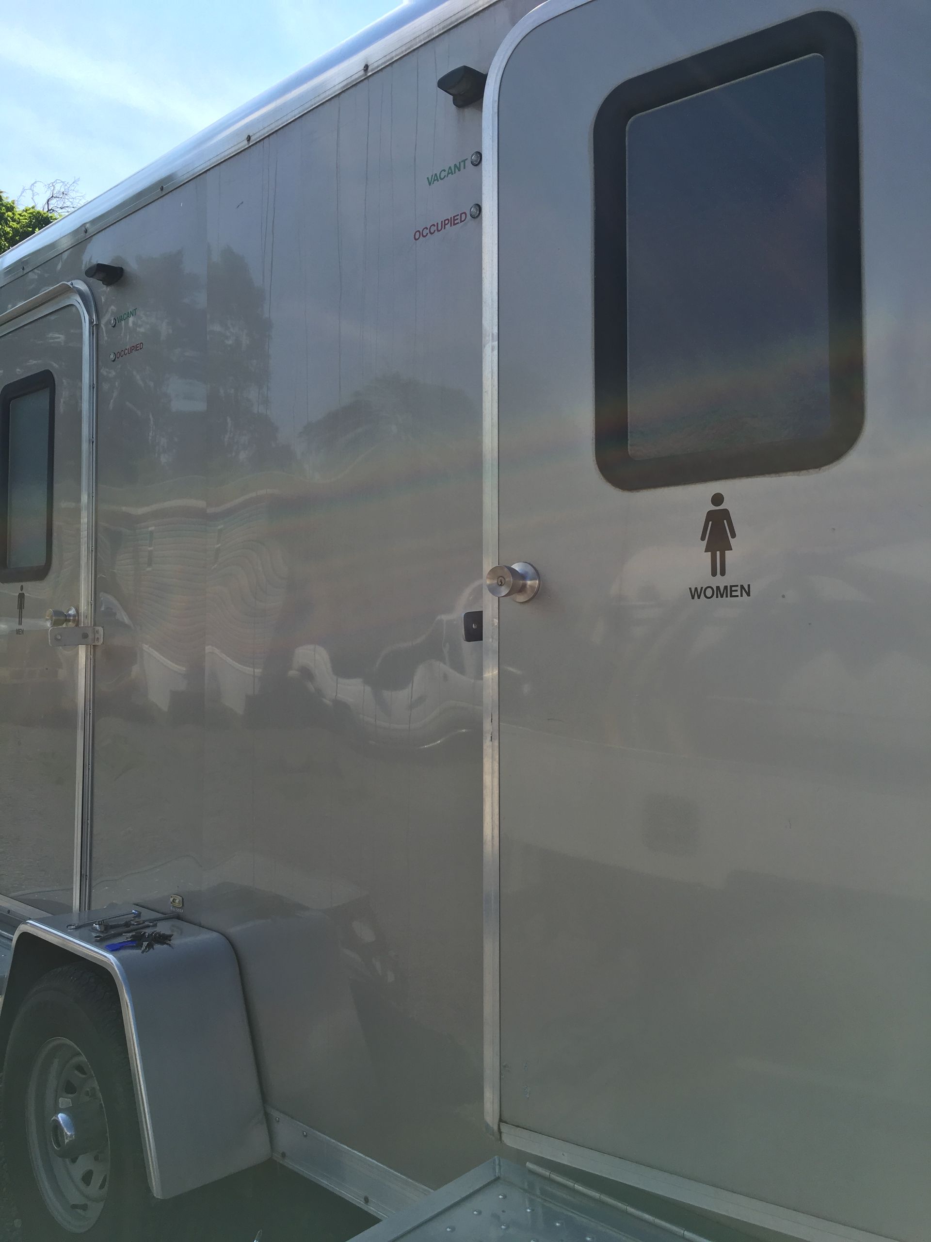 Gray enclosed trailer with a side door and window parked outdoors.