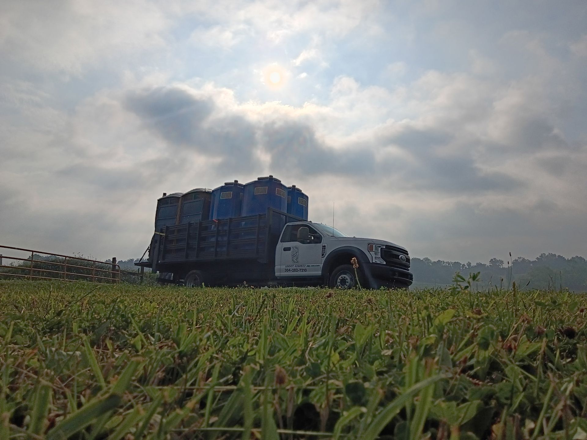Blue cargo truck on a grassy field under a cloudy sky