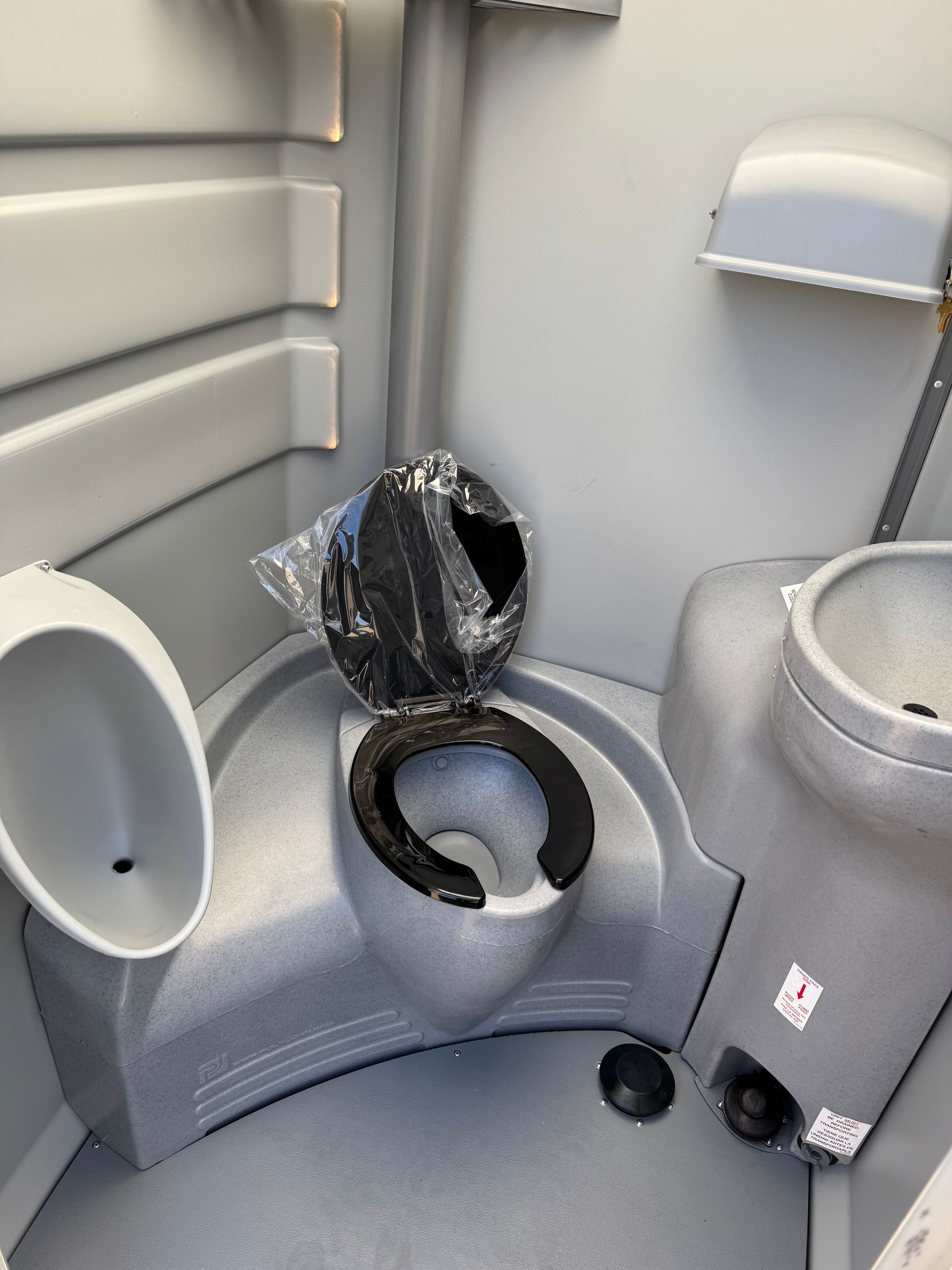 Public restroom stall with toilet, open lid, and gray partition walls; toilet paper holder on the left.