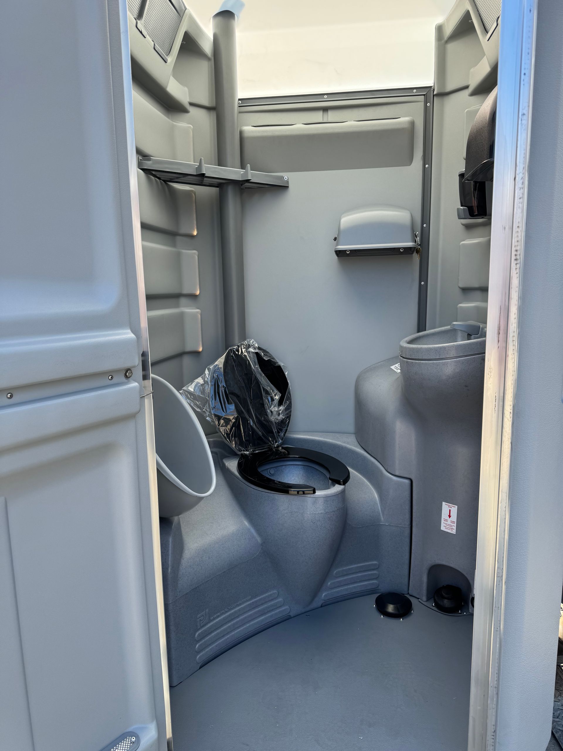 Compact accessible restroom with toilet, gray walls, grab bars, and a sink.