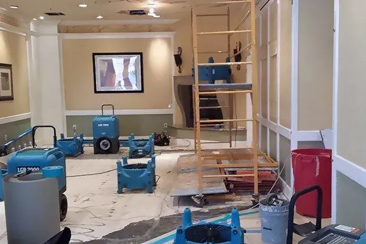 Interior room being dried after water damage. Blue dehumidifiers, scaffolding, and damage visible.