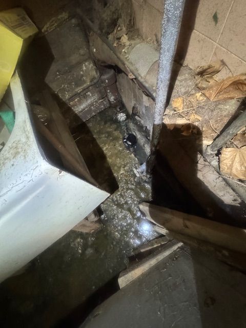 Flooded basement corner with water, debris, and structural elements visible.